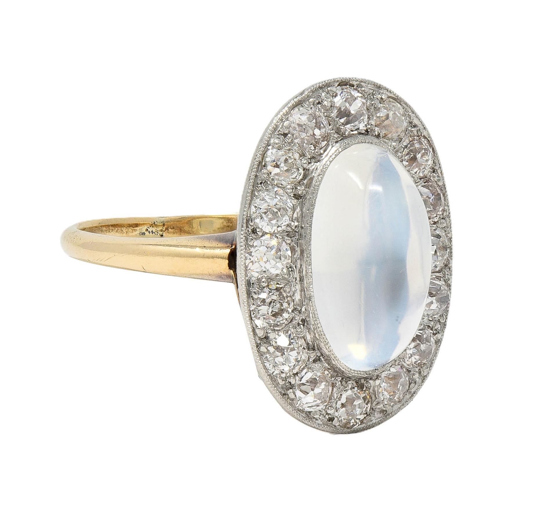 Centering an oval-shaped moonstone cabochon measuring 6.8 x 11.2 mm 
Translucent colorless body displaying blue adularescence 
Bezel set in platinum-topped head with a halo surround
Bead set with old European cut diamonds 
Weighing approximately