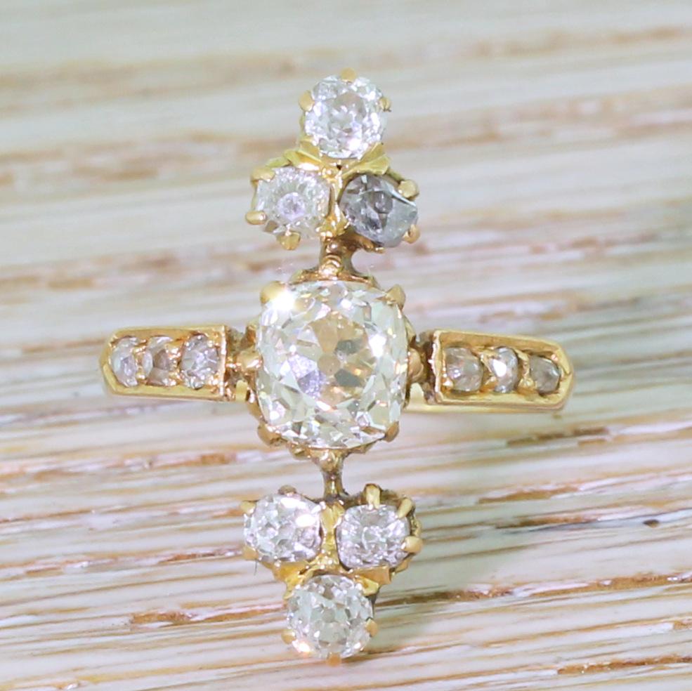 An unashamedly bold piece. This Edwardian diamond ring features a bright, internally clean and lively cushion shaped old mine cut diamond in the centre, secured in a eight-claw ‘cup’ collet and is framed, at the top and bottom, by a pair if trefoil