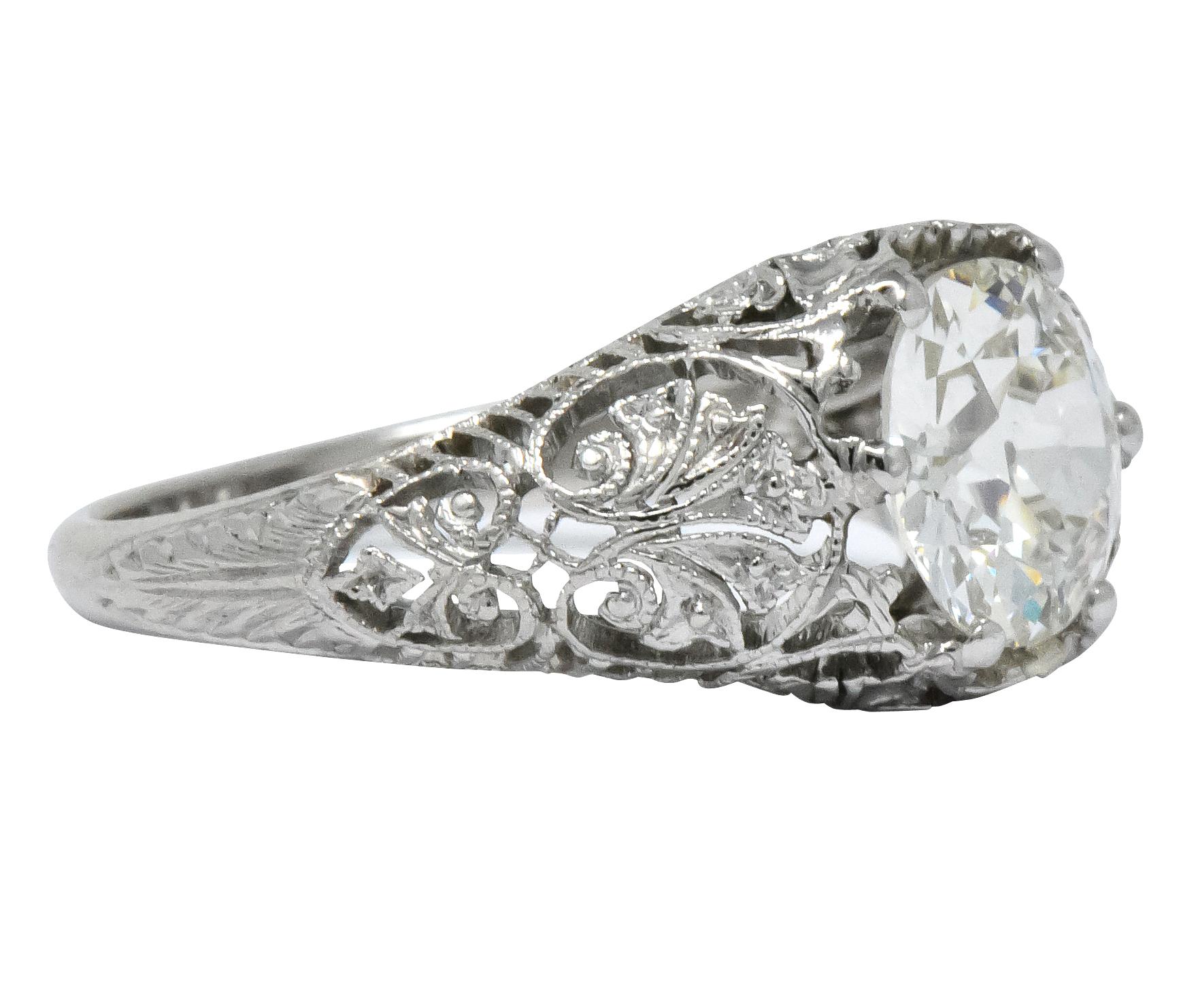 Centering an old European brilliant cut diamond weighing 1.25 carats, K color and VS2 clarity

Stylized foliate accompanied by ornately pieced shoulders and gallery, with partially engraved shank

Inscribed with initials

Tested as platinum

Ring