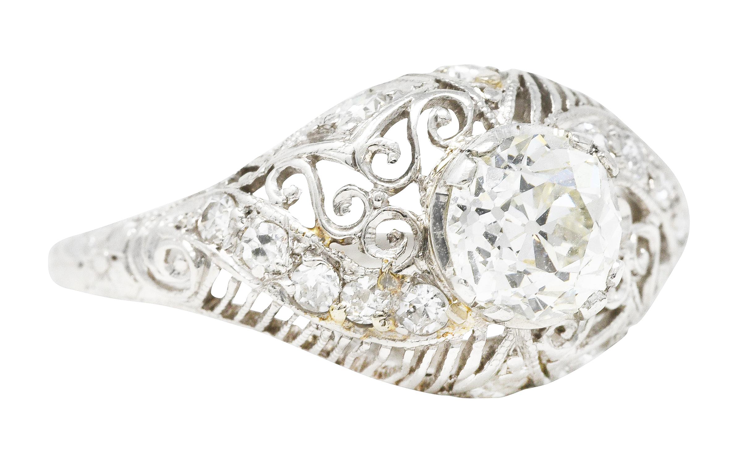 Bombè band ring is pierced with linear striation alternating with scrolled filigree. Centering an old mine cut diamond weighing 0.95 carat - J color with VS2 clarity. With single cut diamond accents weighing collectively approximately 0.30 - eye