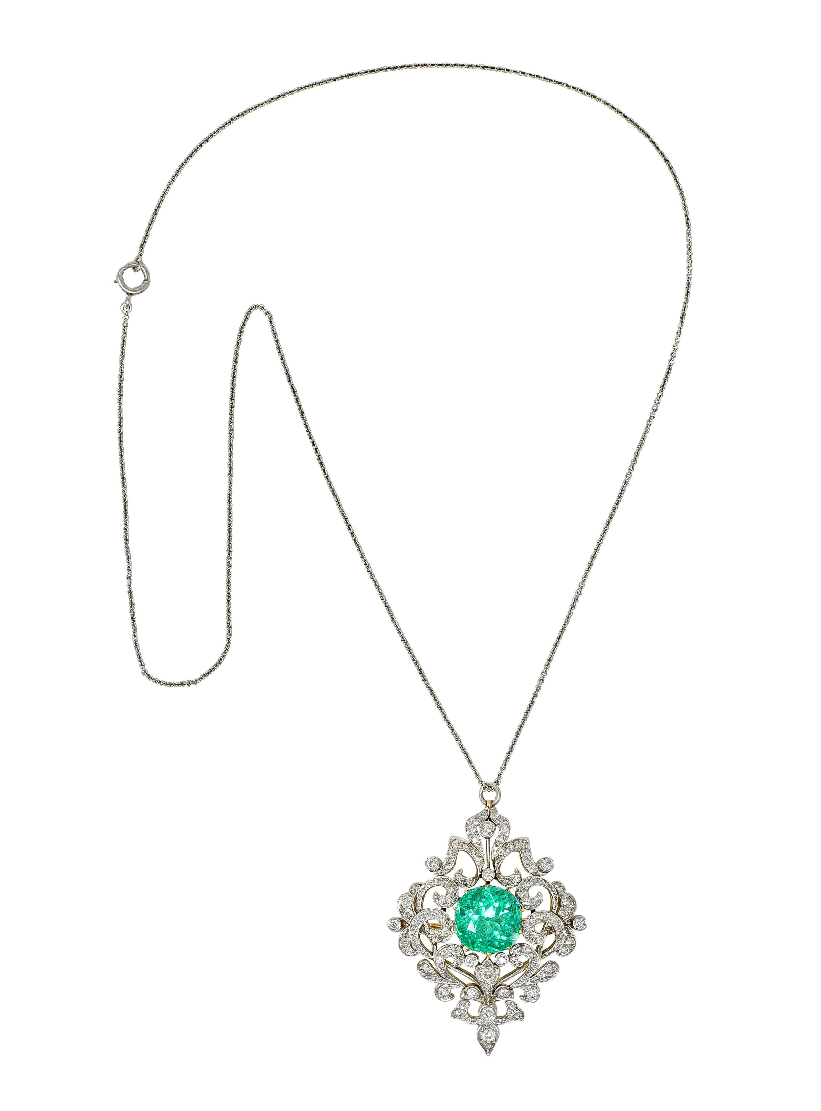 Designed as a 1.5 mm cable link chain suspending an ornately pierced scroll motif pendant 
Centering a cushion cut emerald weighing 10.35 carats - transparent bright green
Natural Colombian in origin with traditional clarity enhancement
Prong set in