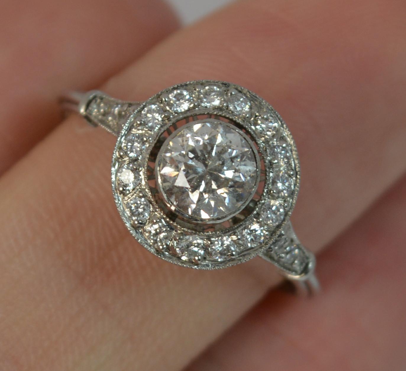 A Platinum and Diamond set ladies target or halo designed ring.

Platinum shank and collet setting.

Set with an old cut diamond to the centre, 5.9mm diameter, 0.90 carats approx. Surrounding are smaller natural diamonds and further diamonds to the