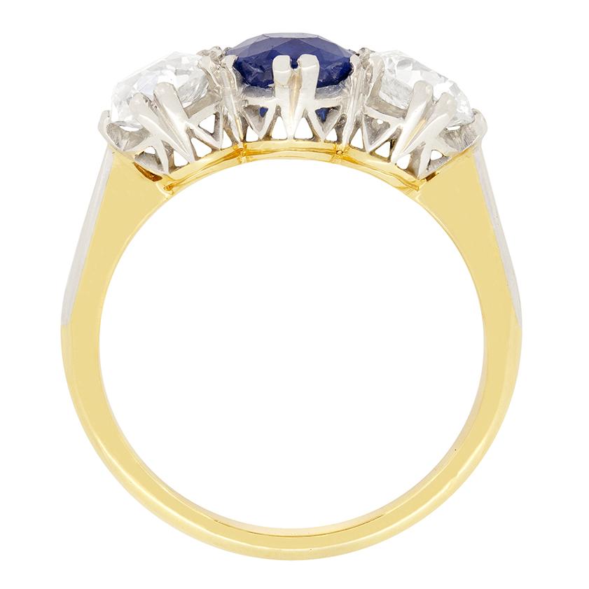 This Edwardian trilogy ring features a stunning natural and unheated sapphire in its centre, flanked by a pair of old cut diamonds. The central sapphire is an oval cut stone weighing 1.30 carat. Each diamond is 0.85 carat and match in quality, H in