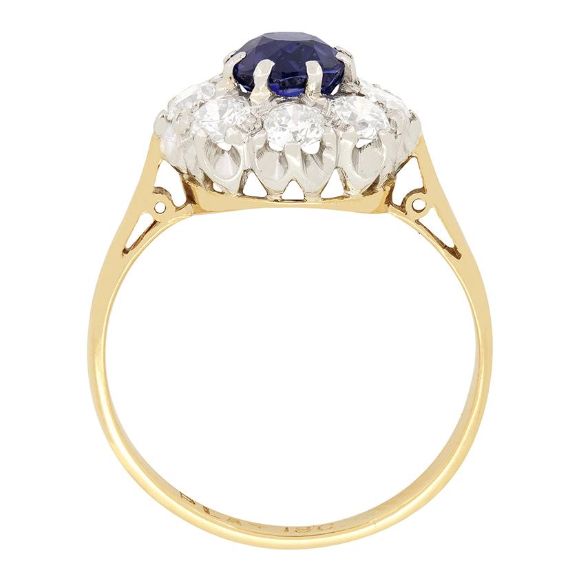 Dieser wunderschöne edwardianische Ring zeigt einen lebhaften Saphir, der von einer Gruppe von Diamanten umhüllt ist. Der tiefblaue Saphir ist ein oval geschliffener Stein mit einem Gewicht von 1,35 Karat, der in Platin gefasst ist. Die umlaufenden