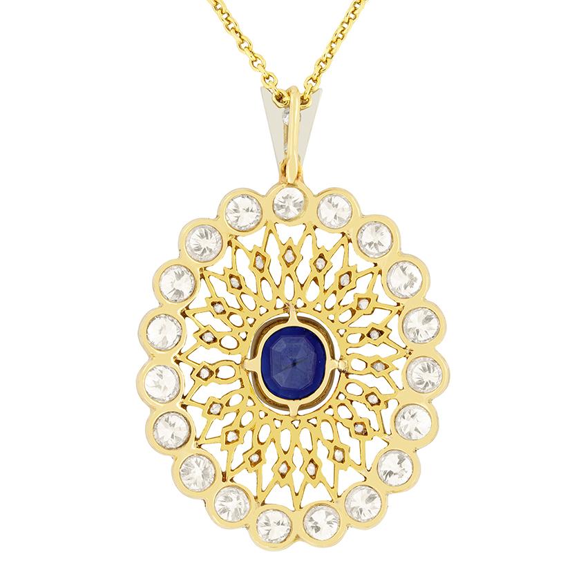 A strikingly beautiful pendant featuring a single natural, unheated blue sapphire delicately mil grained in the centre. It has a weight of 1.35 carat and is an old cushion cut shape. Surrounding the sapphire, is an intricately hand crafted, open