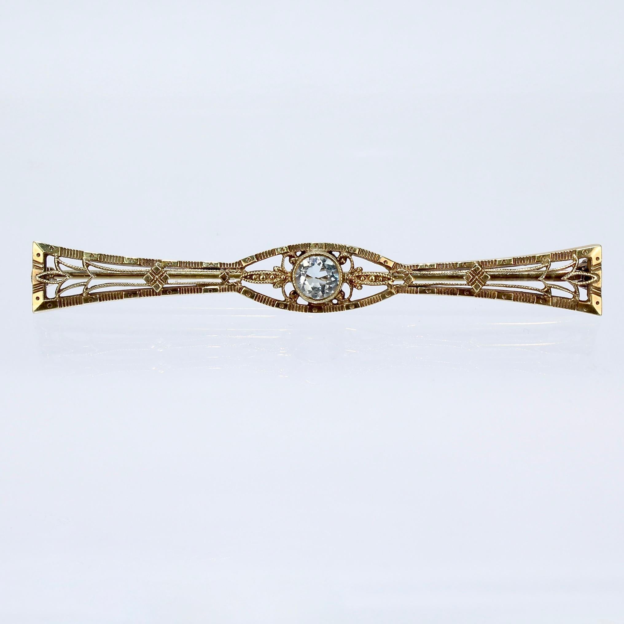 A fine Edwardian gold and aquamarine pin in the form of a bow tie.

With a round light blue aquamarine gemstone set in a gold filigree setting.

Simply a fine, stylish antique pin!

Length: ca. 57 mm

Items purchased from this dealer must delight