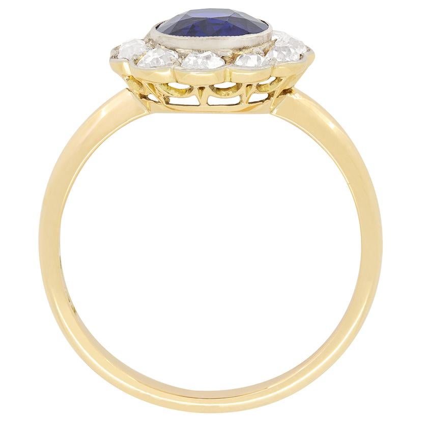 An impressive natural and unheated sapphire sits central to this Edwardian, coronet cluster ring. The deep blue sapphire is an old cut stone, weighing 1.40 carat. Rub over set into platinum claws, the central gem is surrounded by a sparkling cluster
