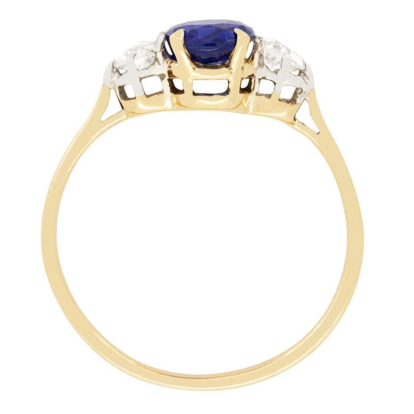 A stunning Sapphire sits accompanied by two old cut diamonds in this Edwardian trilogy ring. The central sapphire is an oval cut stone weighing 1.40 carat. Completely natural and unheated the vivid blue of the sapphire is beautiful. The flanking