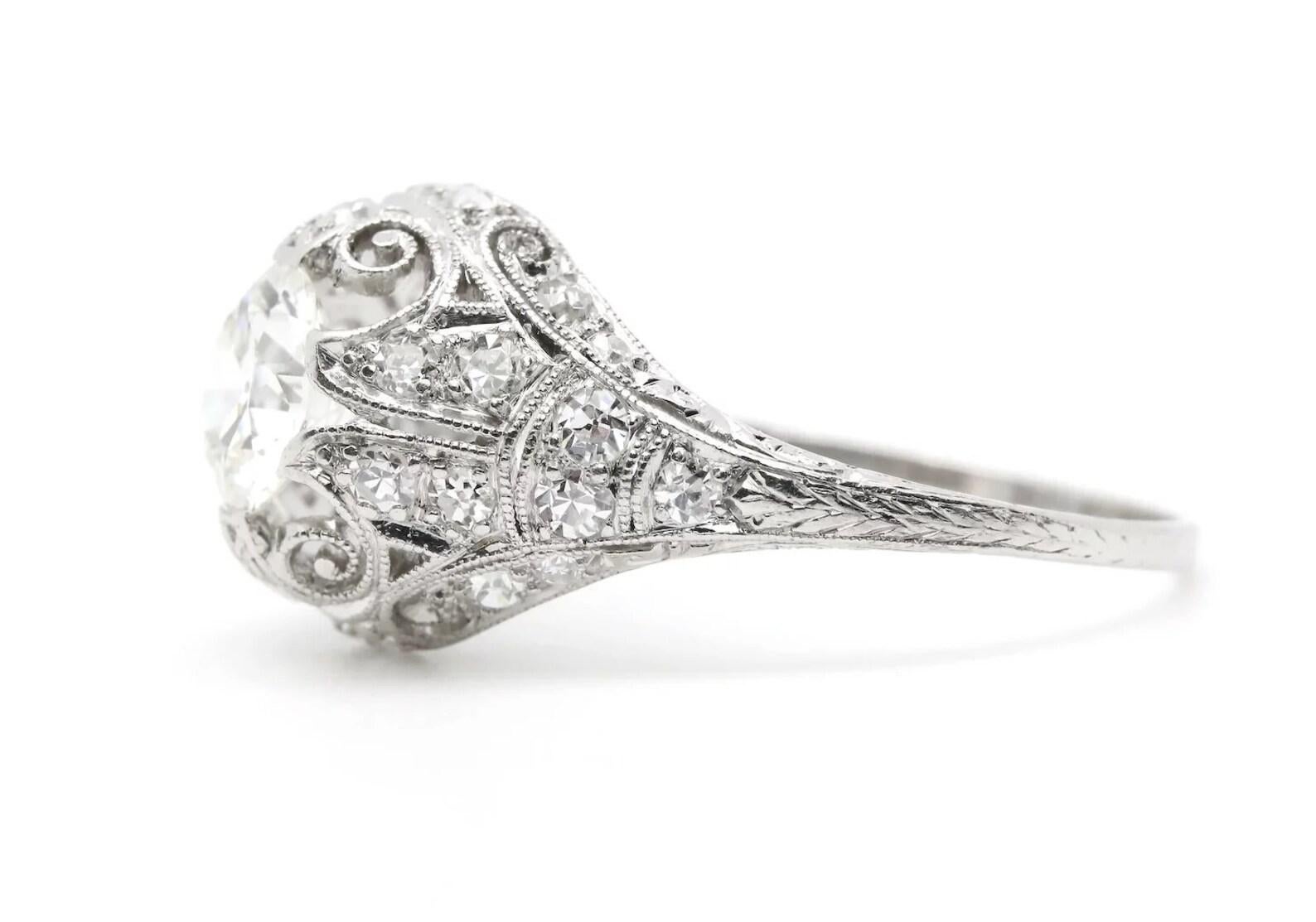A beautiful handmade Edwardian period diamond engagement ring in platinum. Centered by a 0.85 carat H color VS1 clarity antique European cut diamond secured by six unique claw form prongs. Accenting the handmade mounting are 28 pave set European cut