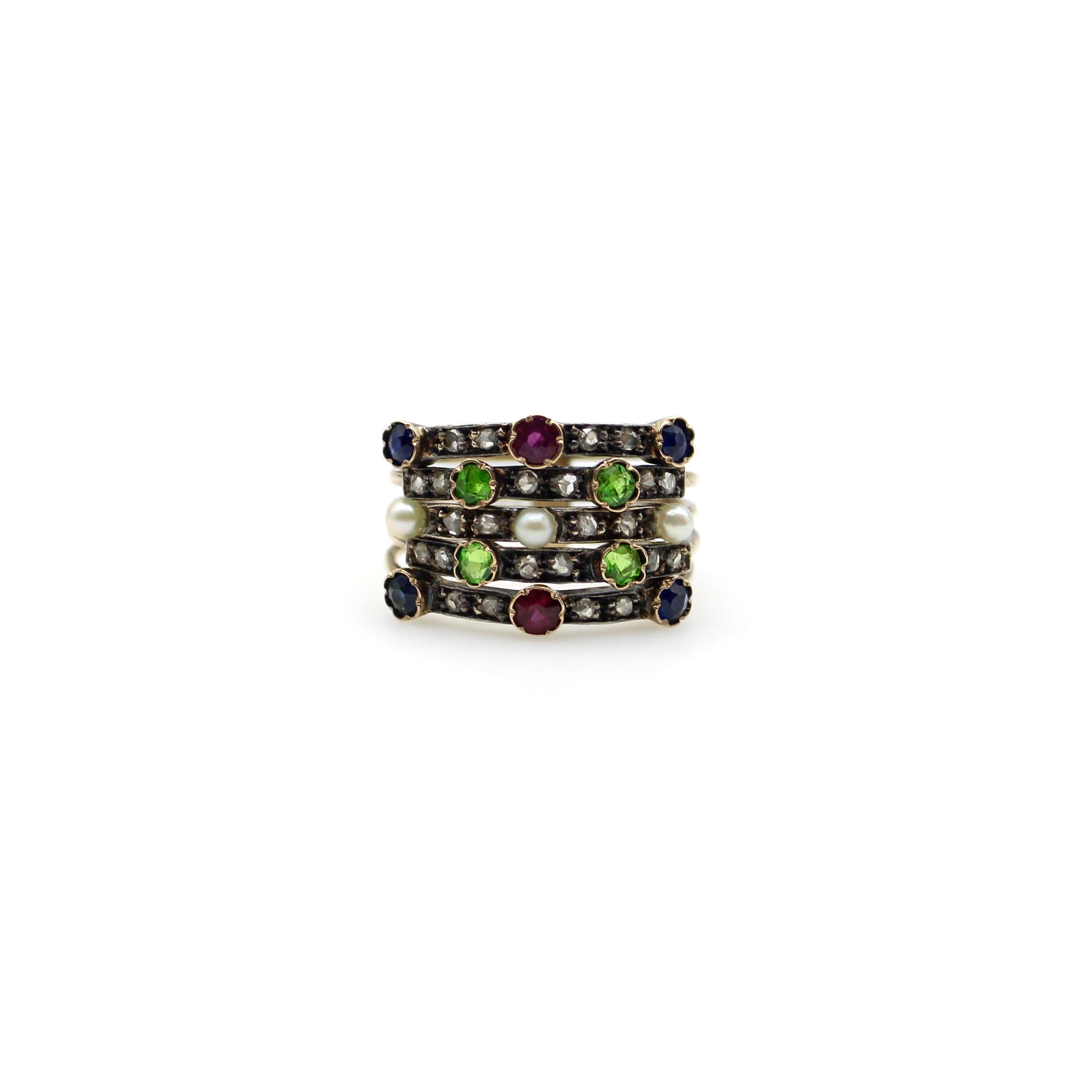 This beautiful 14k gold Edwardian harem ring contains an array of Rose Cut diamonds, pearls, sapphires, rubies, and green demantoid garnets. The ring consists of five 14k gold bands, held together at the bottom in a half-hoop that connects the bands