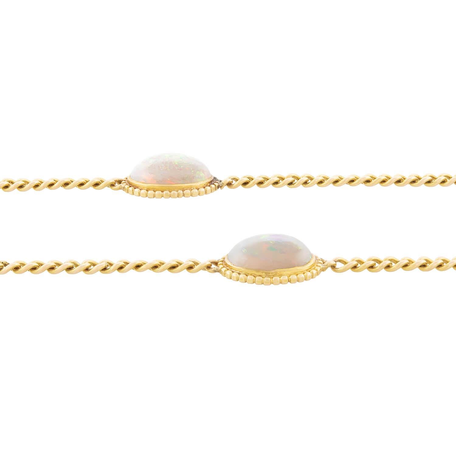 A stunning opal watch chain from the Edwardian (ca1910) era! This elegant piece is crafted in 14k yellow gold, and features 10 bezel set opals strung on a dainty chain. The white oval cut opal cabochons have lovely flashes of blue, green, red,