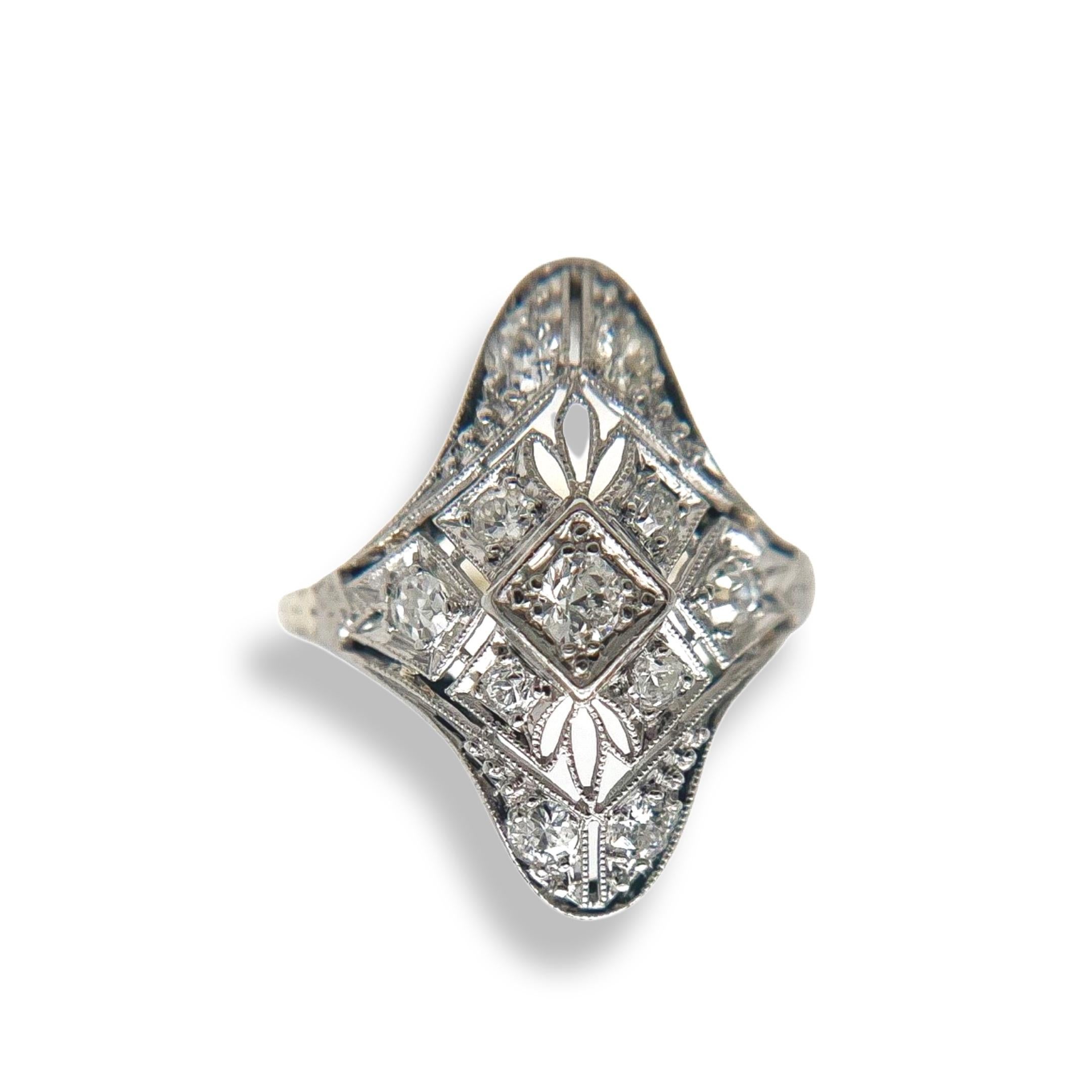 Cette bague ancienne en diamant a été fabriquée à la main au cours de la période de conception édouardienne (1900-1920). La monture en or blanc 14 carats présente un filigrane complexe, des accents de milgrain précis et de magnifiques gravures à la