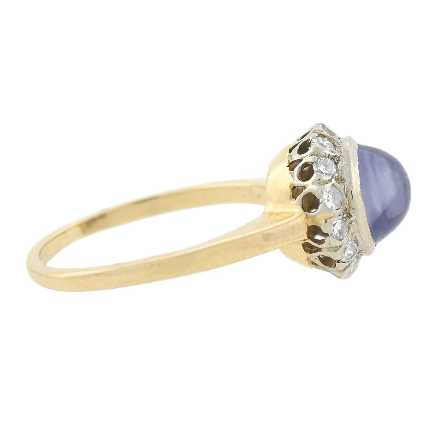 A beautiful, handmade star sapphire ring from the Edwardian (ca1910s) era! Crafted in 14kt yellow and white gold, this lovely piece features a light blue star sapphire cabochon resting in the center. The stone is bezel set and encircled by fourteen