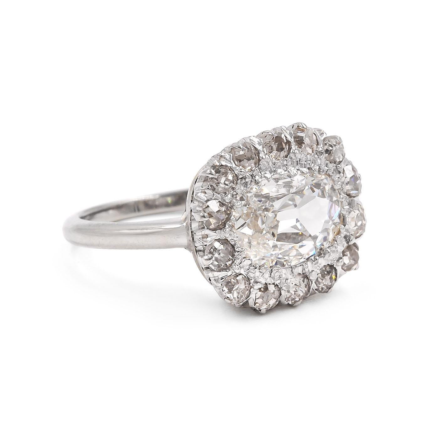 Edwardian era 1.50 Carat Cushion Cut Diamond Cluster Engagement Ring composed of platinum and 18k white gold. Featuring a 1.50 carat Cushion Cut diamond that is GIA certified I color & SI2 clarity, set horizontally and surrounded by 14 Old Mine Cut