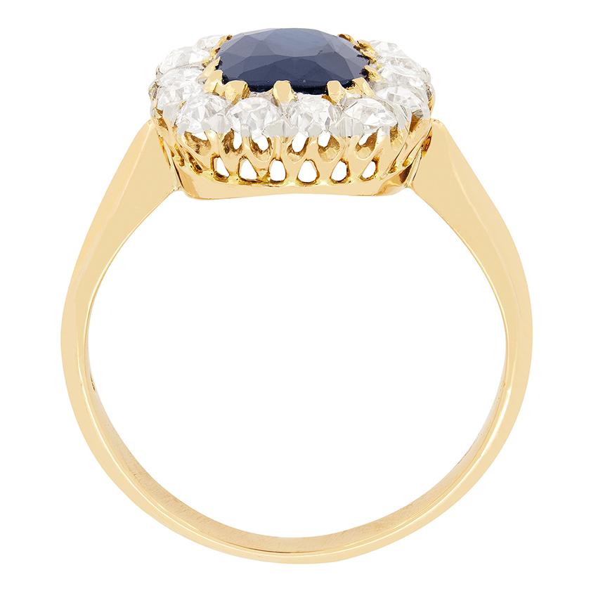 Ein intensiver, tiefblauer Saphir steht im Mittelpunkt dieses edwardianischen Clusterrings. Der 1,50 Karat schwere Saphir ist vollkommen natürlich und unerhitzt und in kontrastierendem 18 Karat Gelbgold gefasst. Um den Saphir herum ist eine Gruppe