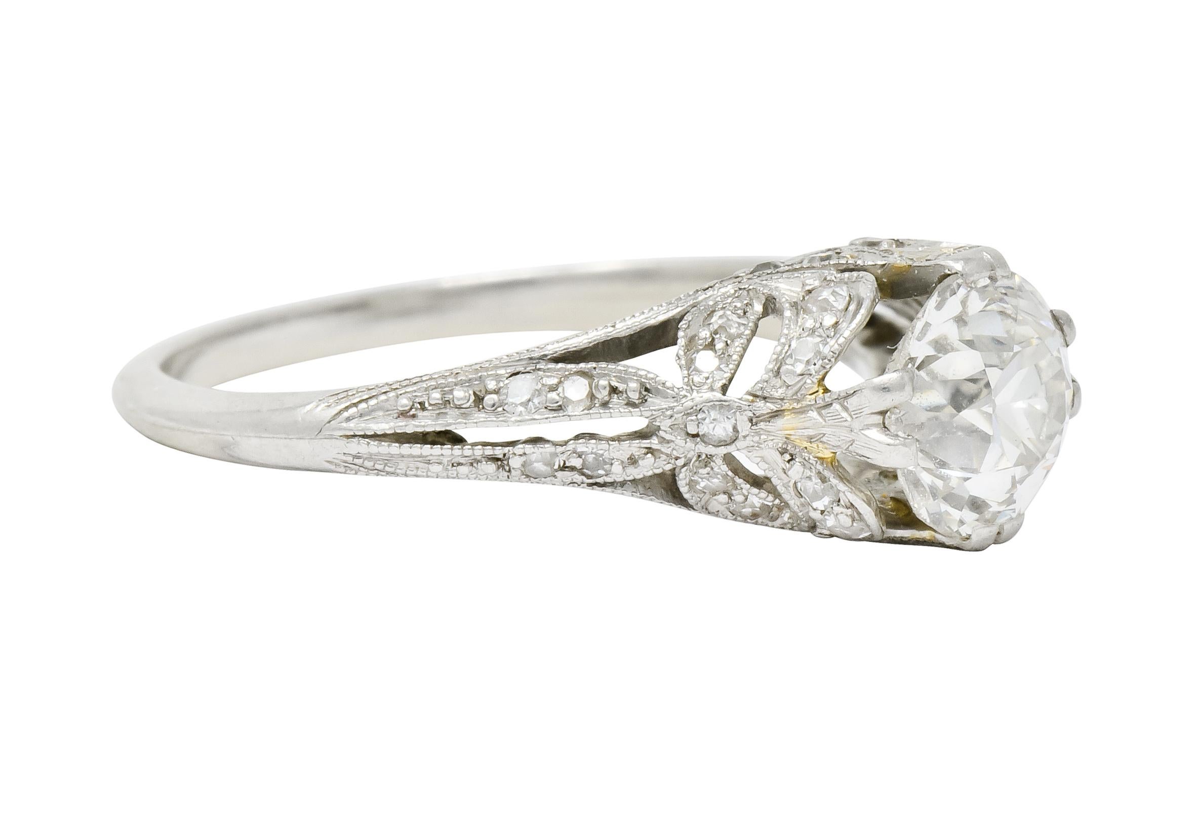 Centering on old European cut diamond weighing approximately 1.02 carat, J color with VS clarity

Set by lovely decorative split prongs of pierced milgrain mounting with stylized bow motif shoulders

Accented throughout by old mine cut diamonds