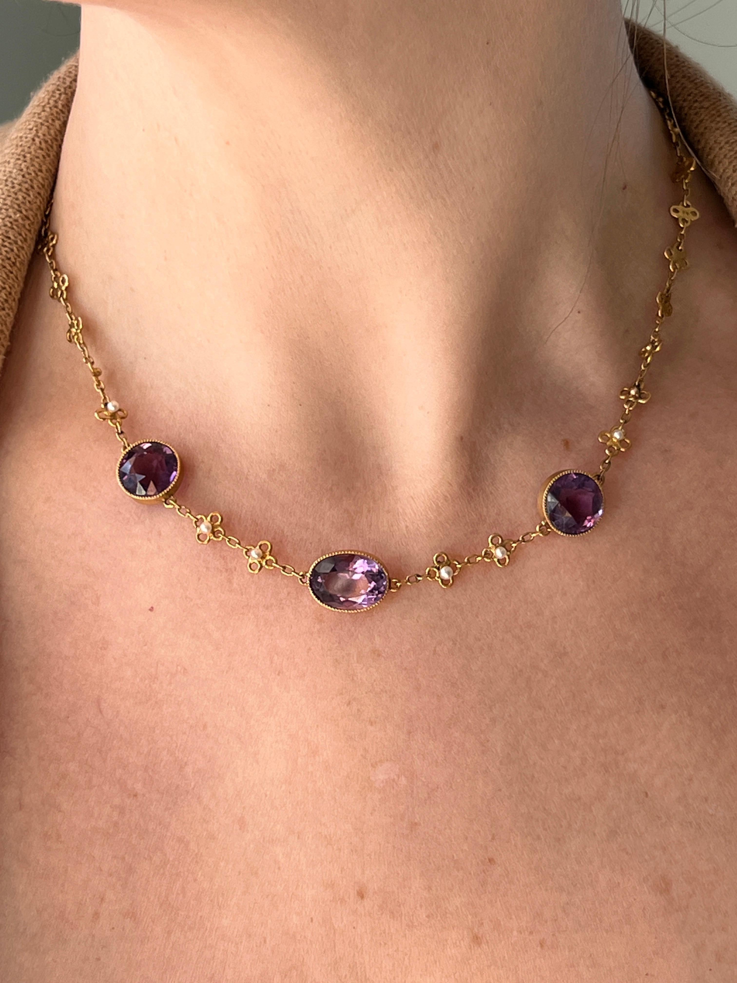 Questa squisita collana di proprietà del 1900 in oro giallo 14K presenta tre ametiste incastonate per un totale di circa 15,35 carati, tra cui un'ovale da 5,45 carati (13,68 x 10,06 mm) e due ametiste rotonde per un totale di 9,9 carati, tutte