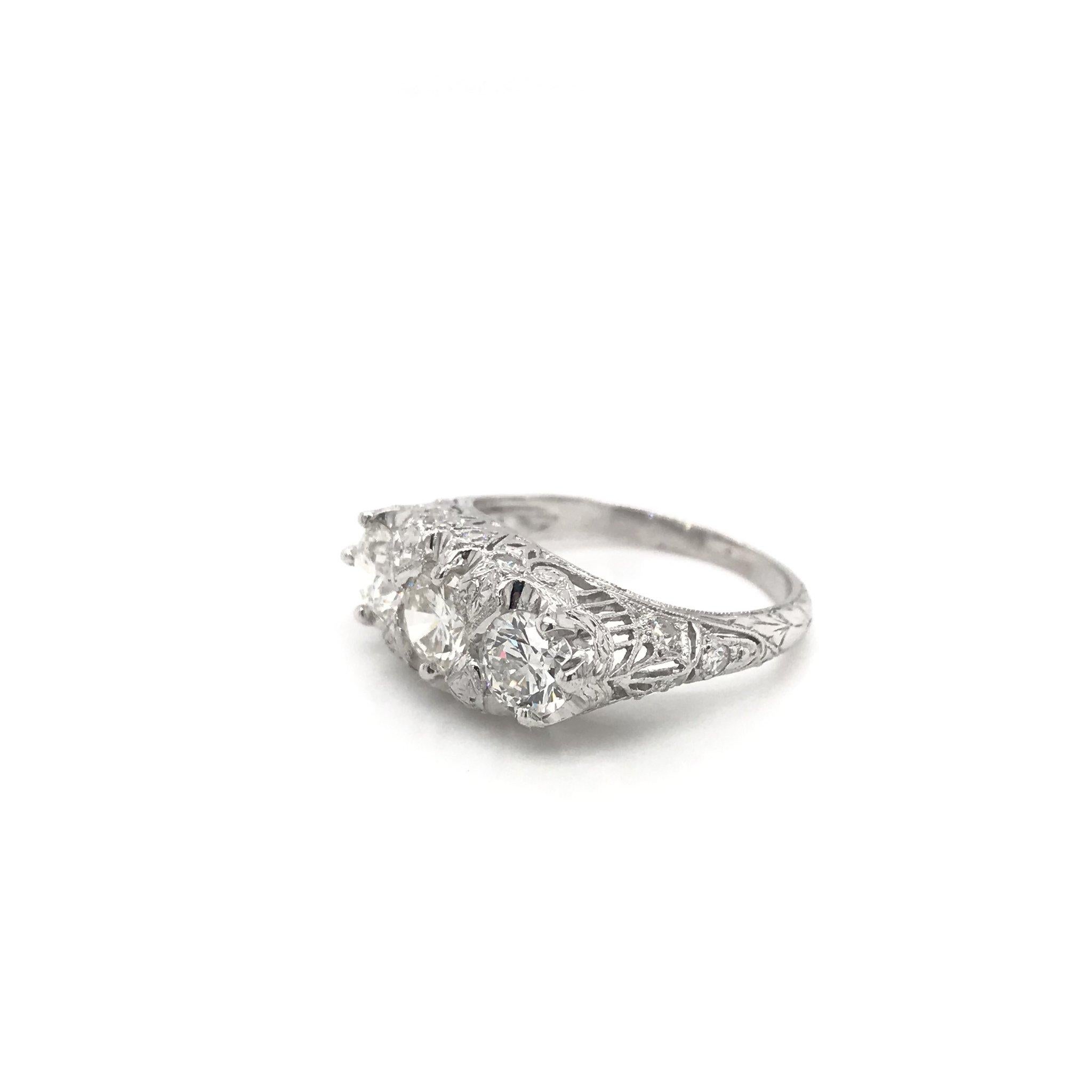 This antique piece was skillfully handcrafted sometime during the Edwardian design period ( 1900-1915 ). The setting features three central diamonds all weighing approximately 0.50 carats each, grading F in color, VS in clarity. The platinum