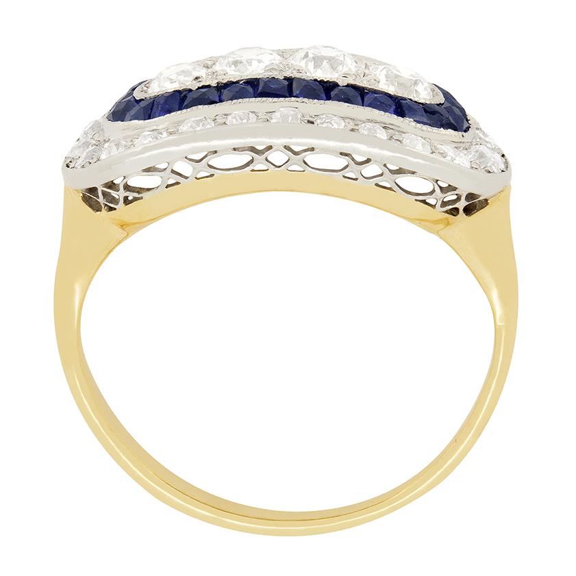 Dating back tot he Edwardian era is this enticing cluster ring featuring a combination of diamonds and sapphires. In the centre, four old cut diamonds totalling to 0.60 carats are surrounded by a striking halo of twenty-four sapphires. These vivid