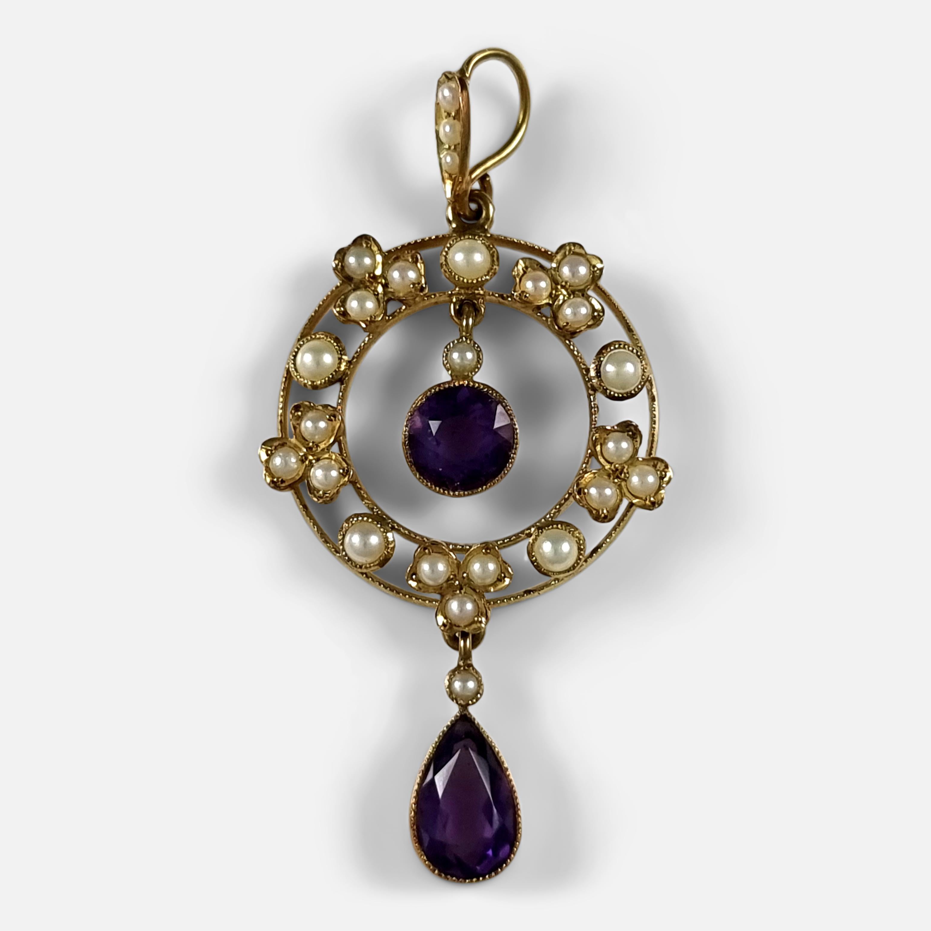An Edwardian 15ct yellow gold amethyst and seed pearl pendant. 

The pendant is stamped '15c' to denote 15ct gold fineness.

Period: - Early 20th century.

Date: - Circa 1905.

Measurement: -  4.4cm (height including bale) x 2.0cm (width) x 0.4cm