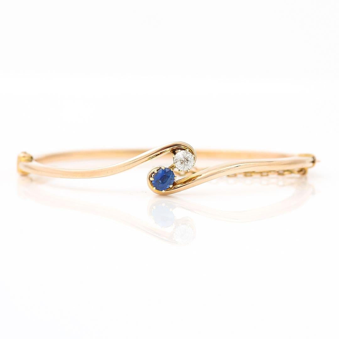 A stunning Edwardian 15ct yellow gold finely crafted bangle set with single oval cut sapphire and old mine cut diamond dating from circa 1905. The head of the bangle is simply and stylishly set with a blue sapphire of 0.30ct along side a 0.20ct old