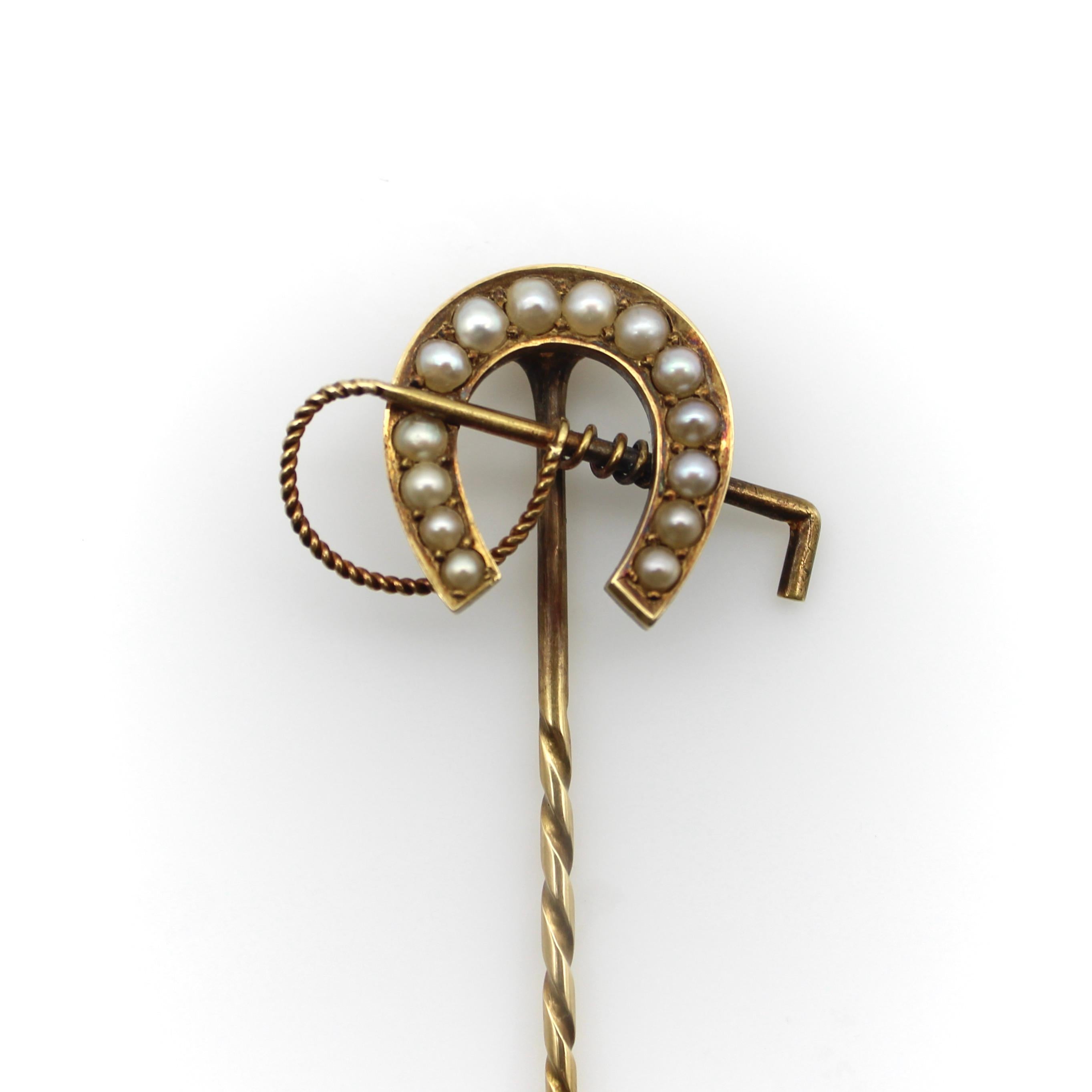This elaborate Edwardian 15 karat yellow gold decorative stick pin features a horseshoe and riding whip. The good-luck horseshoe has 14 pearls that fit nicely inside of it, as if to add a glimmer of good fortune. Each pearl is approximately between
