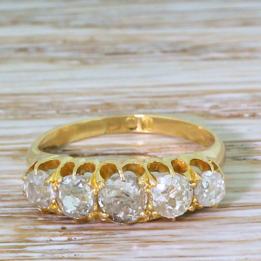 A charming Edwardian five stone diamond ring. The graduating line of old mine cuts are very lively – and very chunky. The diamonds are secured a finely pierced and carved yellow gold gallery, leading to a slim and tapering D-shaped shank.

Cut – Old