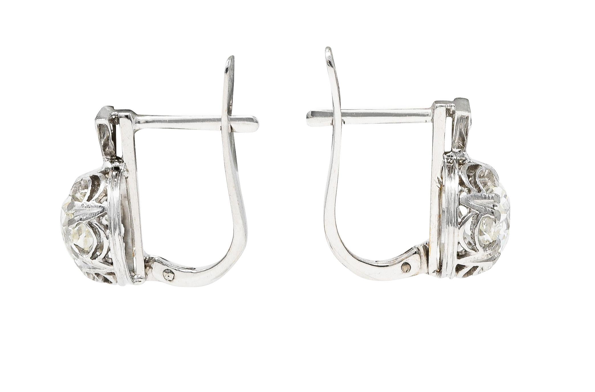Huggie earrings have a triangular form surmount accented by an old single cut diamond. Weighing collectively approximately 0.07 carat with I color and SI clarity. Mounting is decoratively pierced as swagged latticework.  Featuring old mine cut