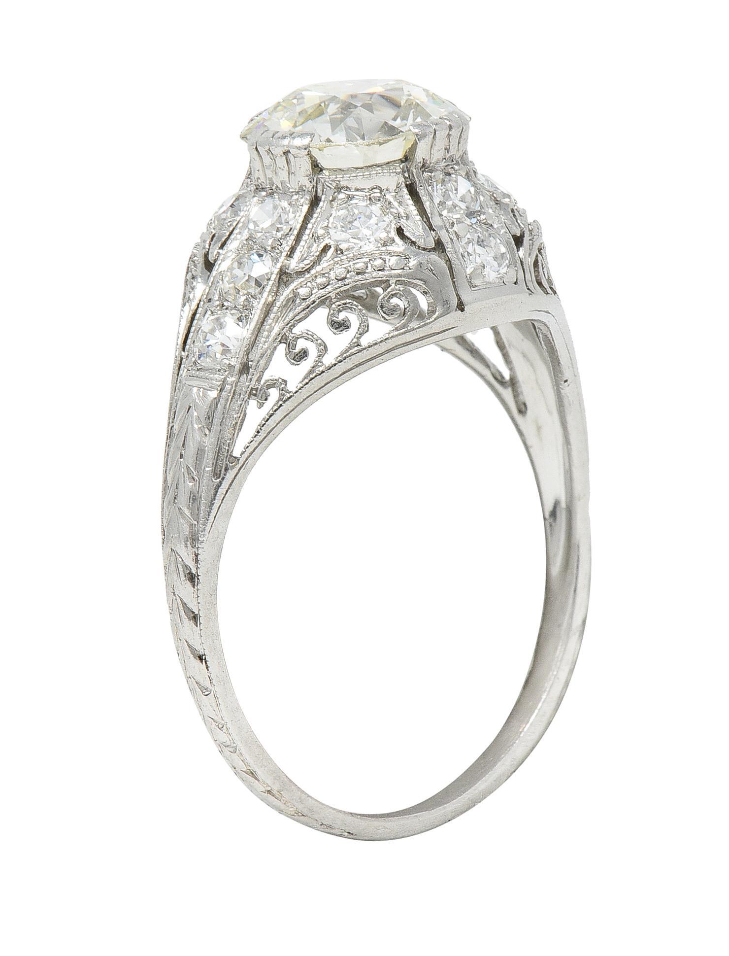 Centering an old European cut diamond weighing approximately 1.31 carats - O color with VS2 clarity 
Set with grooved compass style prongs with a bombay form surround
Featuring pierced scroll motif filigree and miligrain detailing 
With bead set