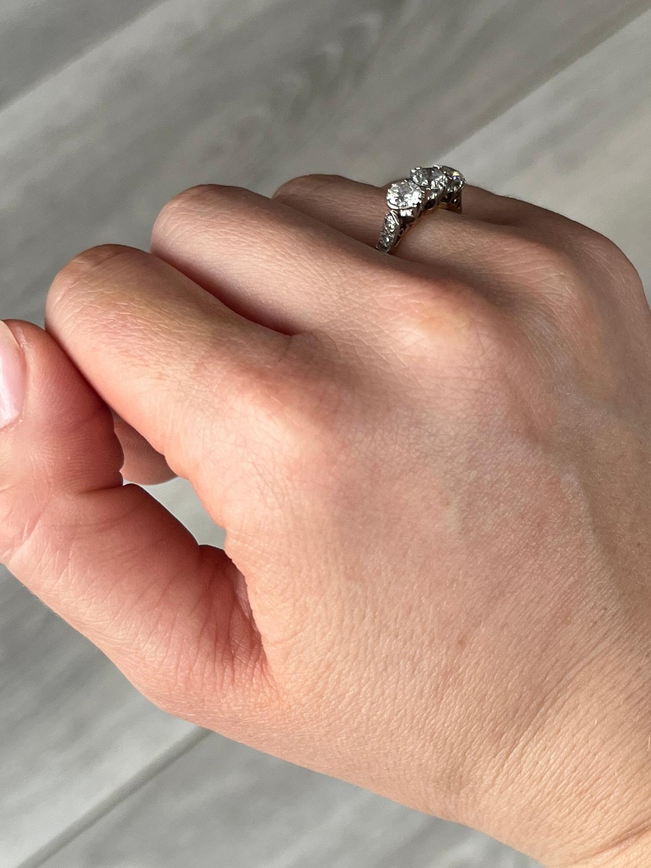 A beautiful diamond three stone ring modelled in 18carat gold and the stones set in platinum. The diamonds are H colour VS1, bright and are old European cut. The central diamond measures 55pts and the smaller ones measure 45pts each. The platinum