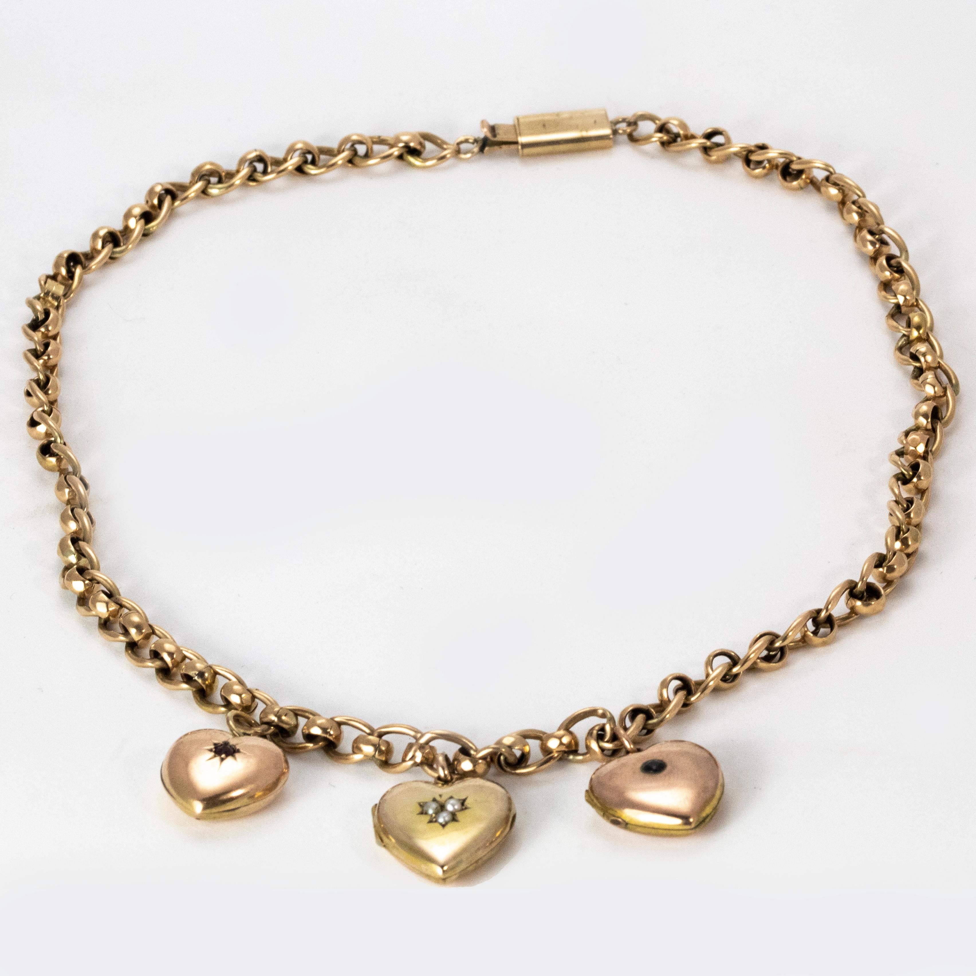 An exquisite 18 karat gold Edwardian necklace with three 9 karat gold hearts. Each heart is delicately set with a sapphire, pearl, and ruby respectively. The pearl and sapphire hearts also function as lockets.

Necklace length: 16 inches