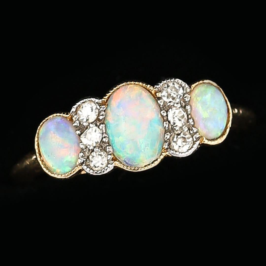 A beautiful Edwardian 18 karat yellow gold, precious opal and diamond three stone ring set with six old cut diamonds. The six diamonds are Early European cut, estimated at 0.04cts per stone ie 0.24cts total. A lovely period example of an antique