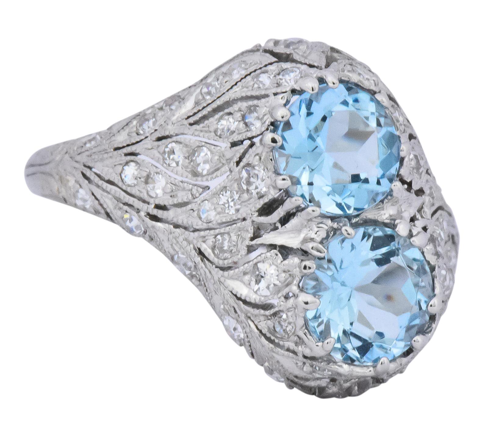 Centering two round aquamarines weighing approximately 1.25 carats total, bright medium blue and very well matched

In a pierced, flowing foliate motif gallery

Set throughout with single and old European cut diamonds, weighing approximately 0.55