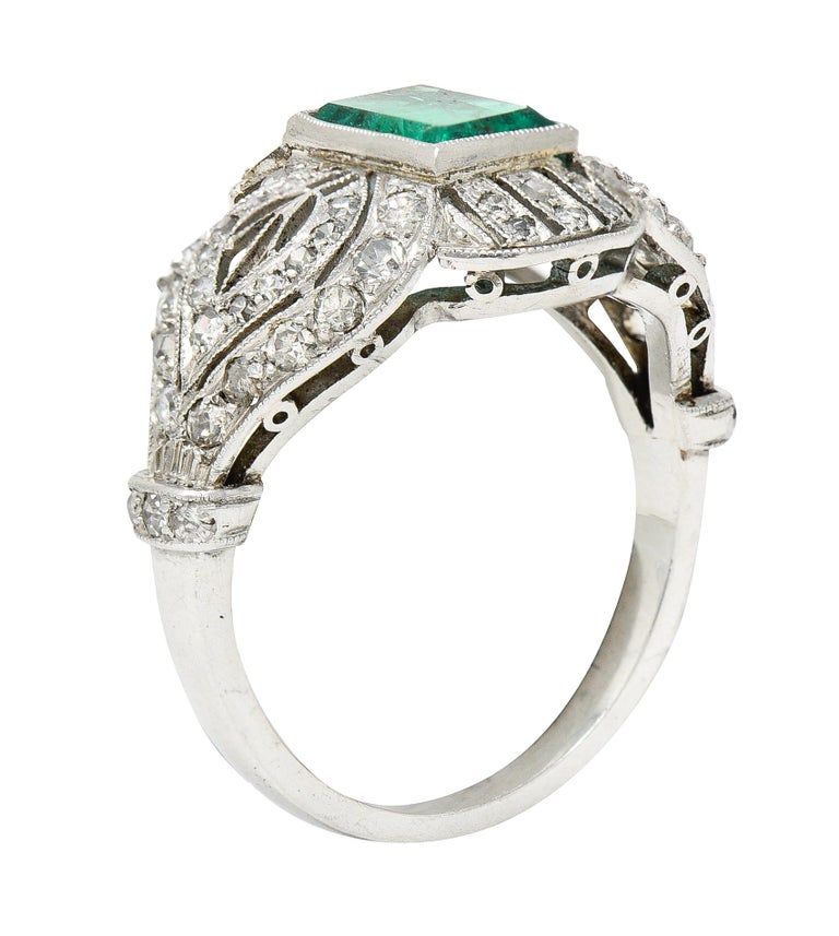 Dinner ring is a stylized quatrefoil form with milgrain edges and pierced striation

Centering a rectangular cut emerald weighing approximately 0.80 carat

Slightly bluish and strongly green in color and semi-transparent with natural