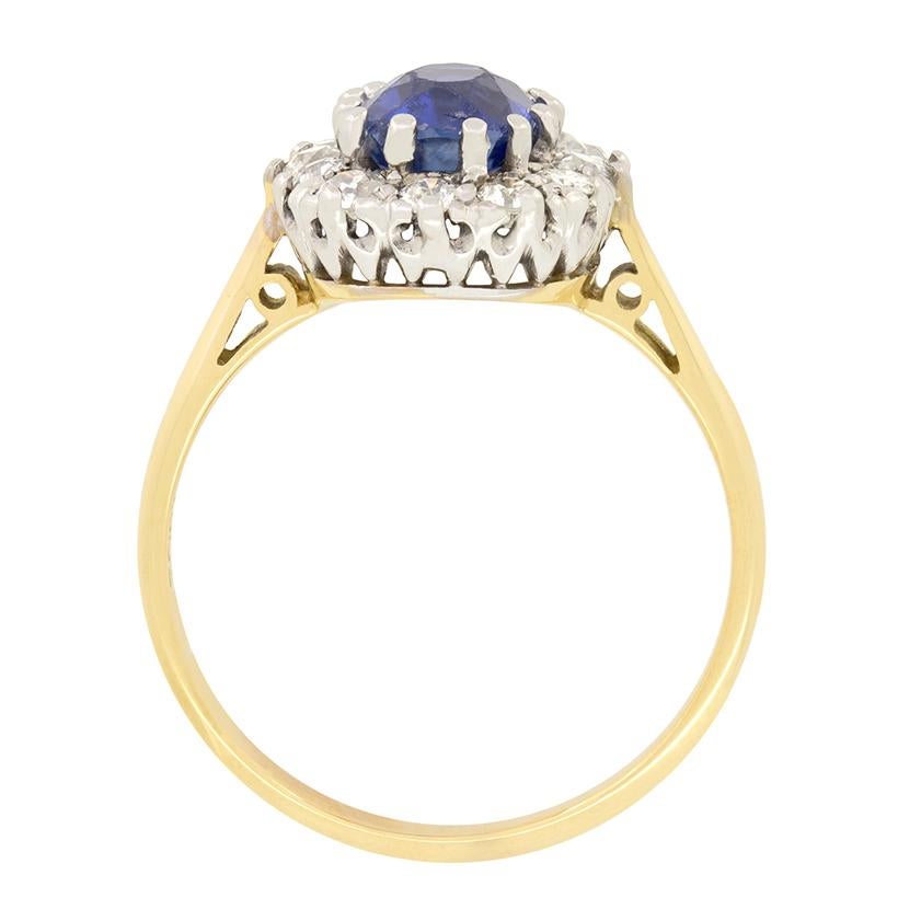 This stunning Edwardian cluster ring features an eye catching 1.80 carat old cushion cut sapphire at its centre. The deep blue sapphire is claw set into platinum, surrounded by a halo of old cut diamonds totalling 0.60 carat. The diamonds all match