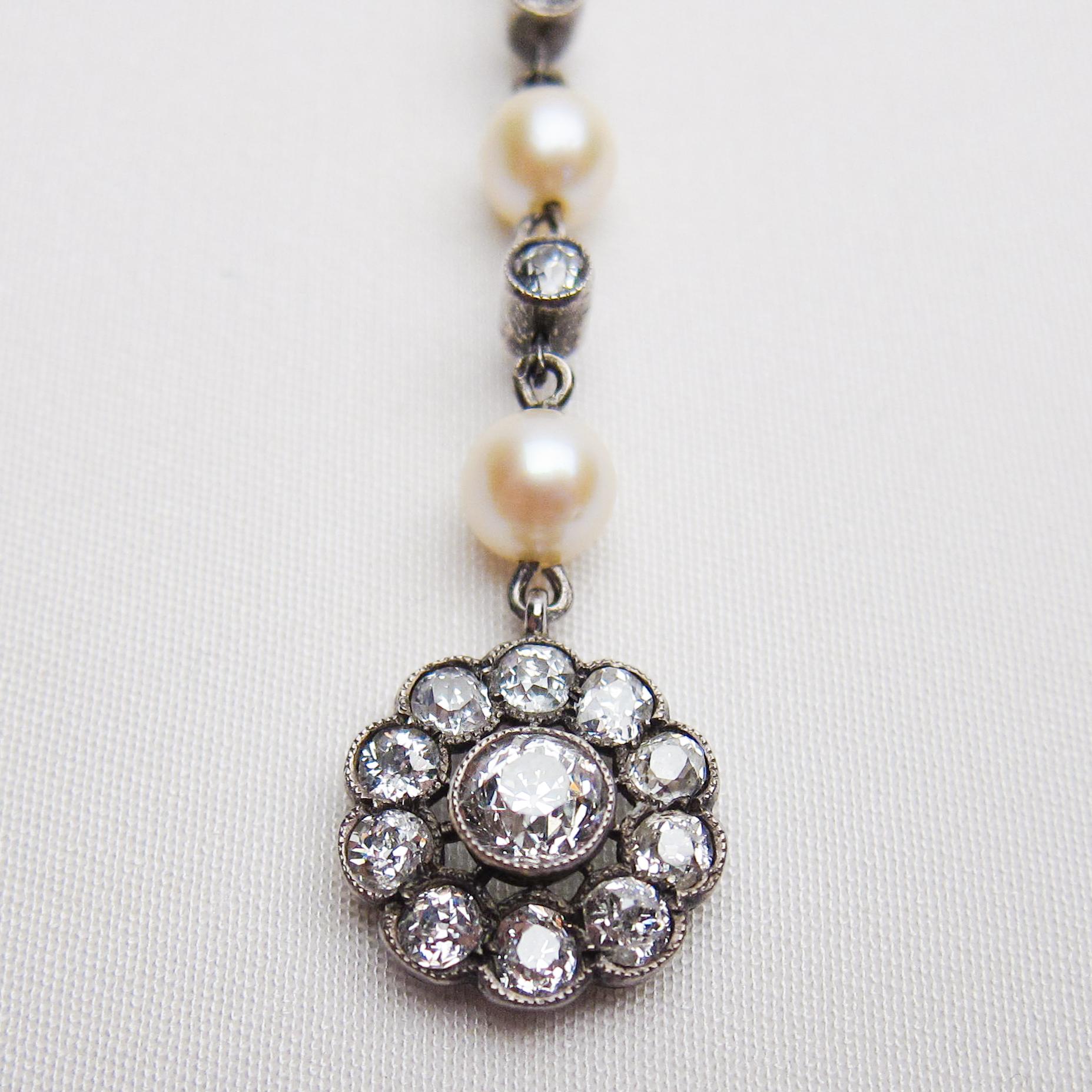 Circa 1910. This stunning Edwardian women's pendant features a cluster setting accented with 11 bezel-set, old European-cut diamonds surmounted by three cultured saltwater pearls, two bezel-set old European-cut diamonds, and 12 bead-set rose-cut