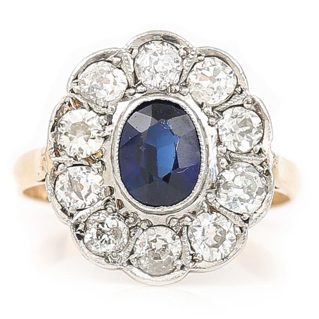 A fabulous early 20th century 1ct oval blue sapphire and 1ct transitional cut diamond halo cluster ring, set in 18ct gold dating from circa 1910. The central set oval sapphire is a deep, violet blue and is rub over set and is surrounded by 10 hand