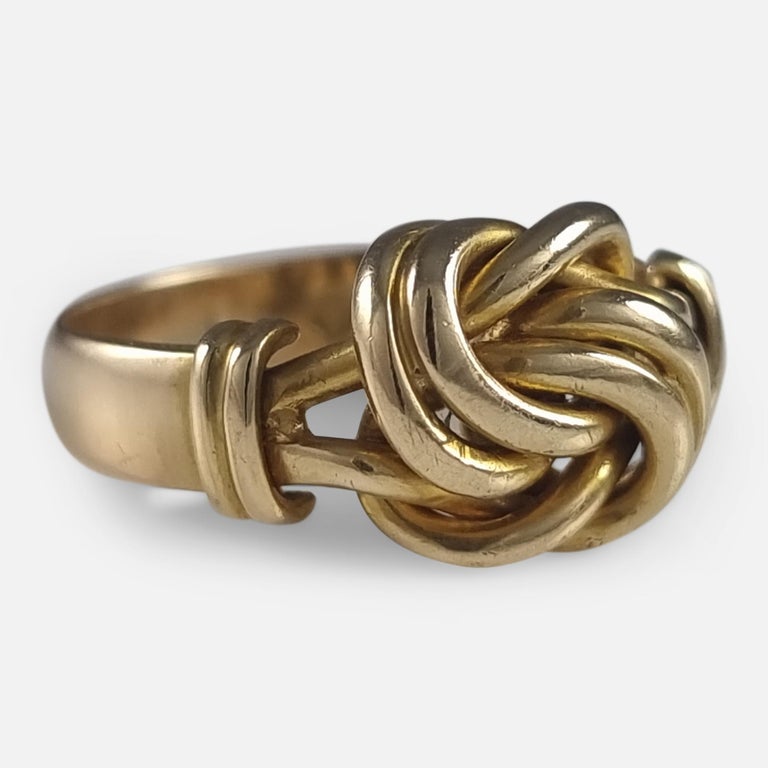 An Edwardian 18ct yellow gold knot ring. The ring is crafted with a closed double knot design to the centre, reeded shoulders, and plain band. Knot rings were traditionally worn to symbolise everlasting love.

The ring is UK hallmarked with the