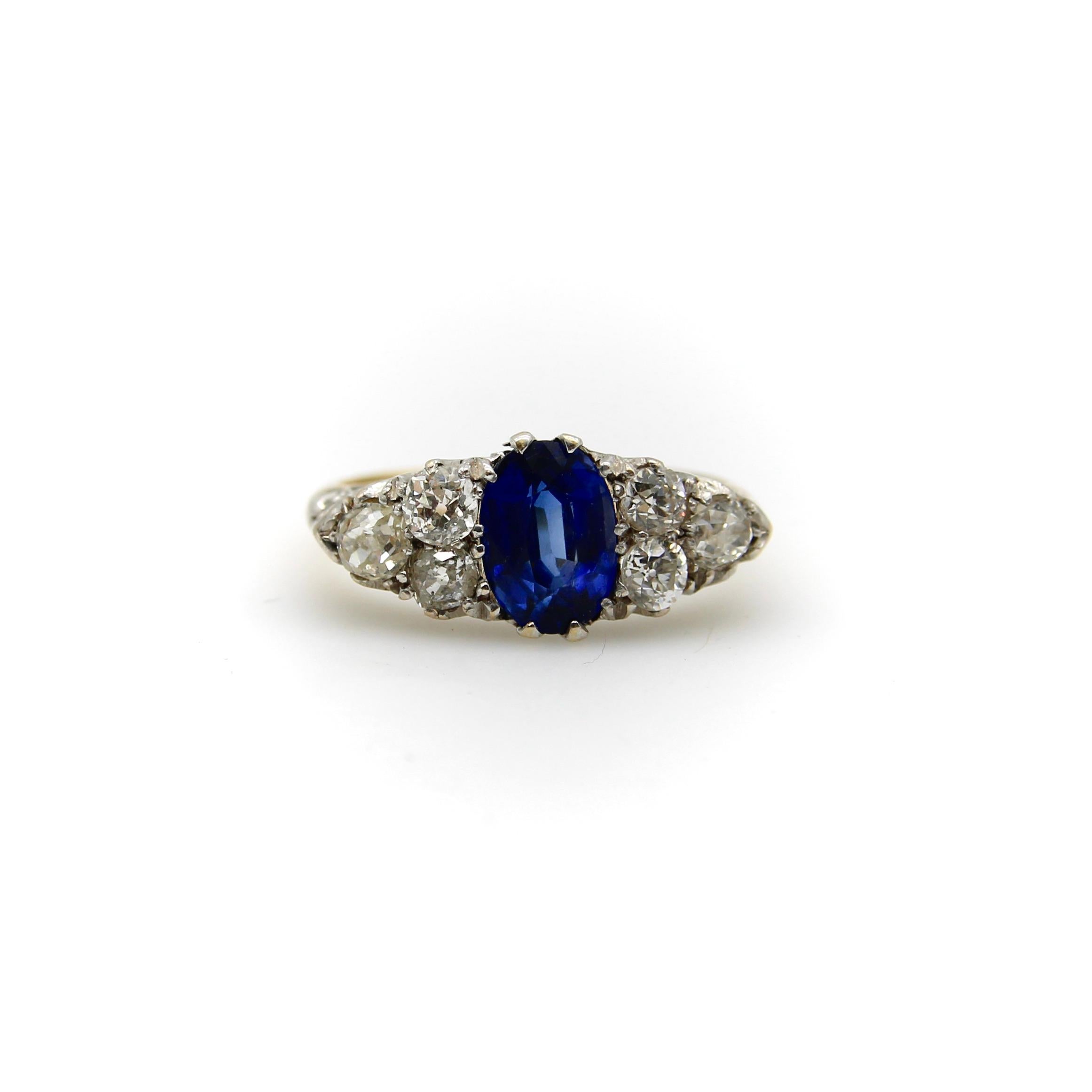 An English Edwardian ring from the year 1913. The ring is platinum and 18k gold with a large sapphire as its centerpiece surrounded by six Old European Cut diamonds. The sapphire is a lively, bright cobalt blue with beautiful saturation. The stone