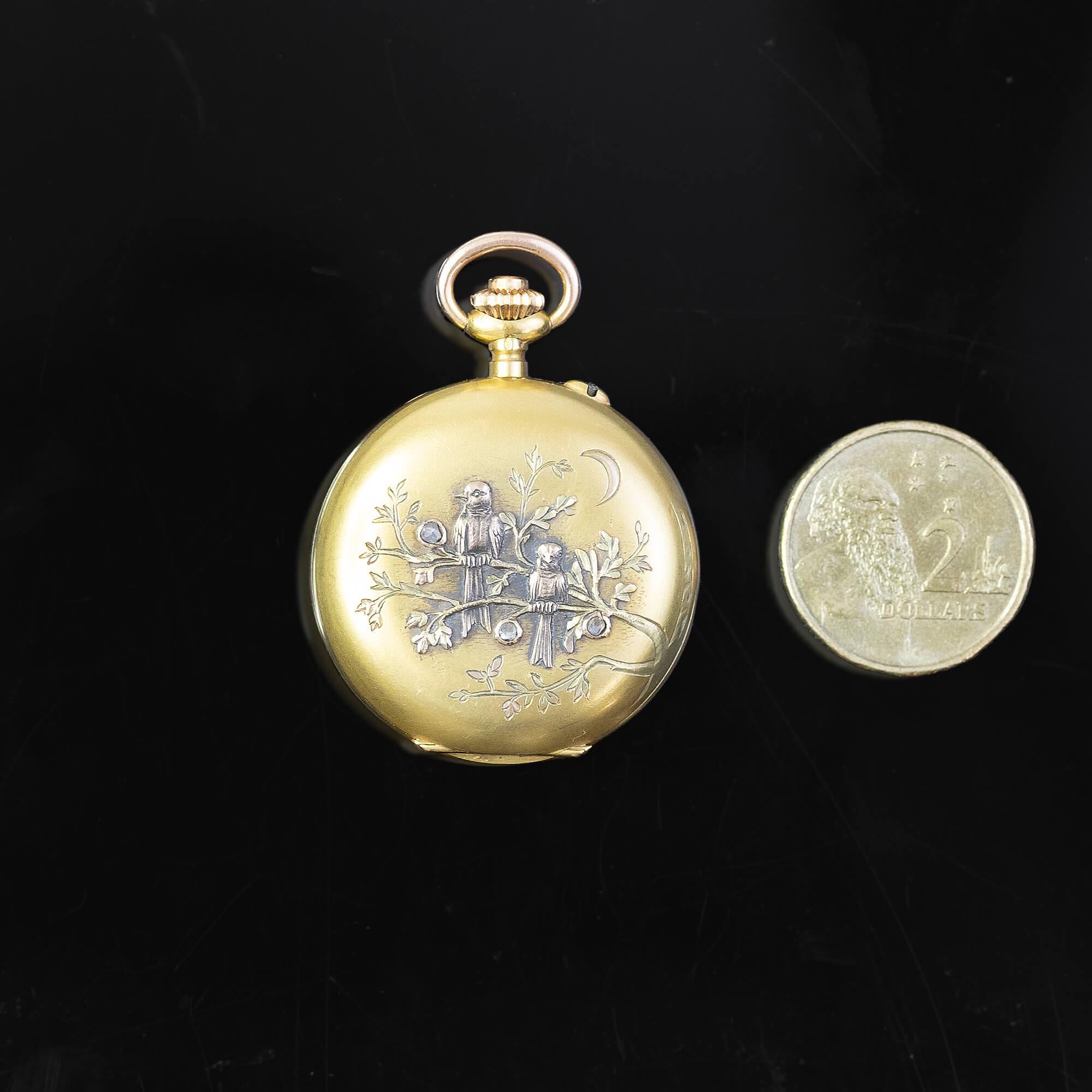 This 18k yellow gold Swiss-made Ladies’ pocket watch features a decorative raised and engraved scene of birds sitting on leafy branches in the night under a crescent moon. Three small rose cut diamonds set as blossoms to add a little sparkle.

18k