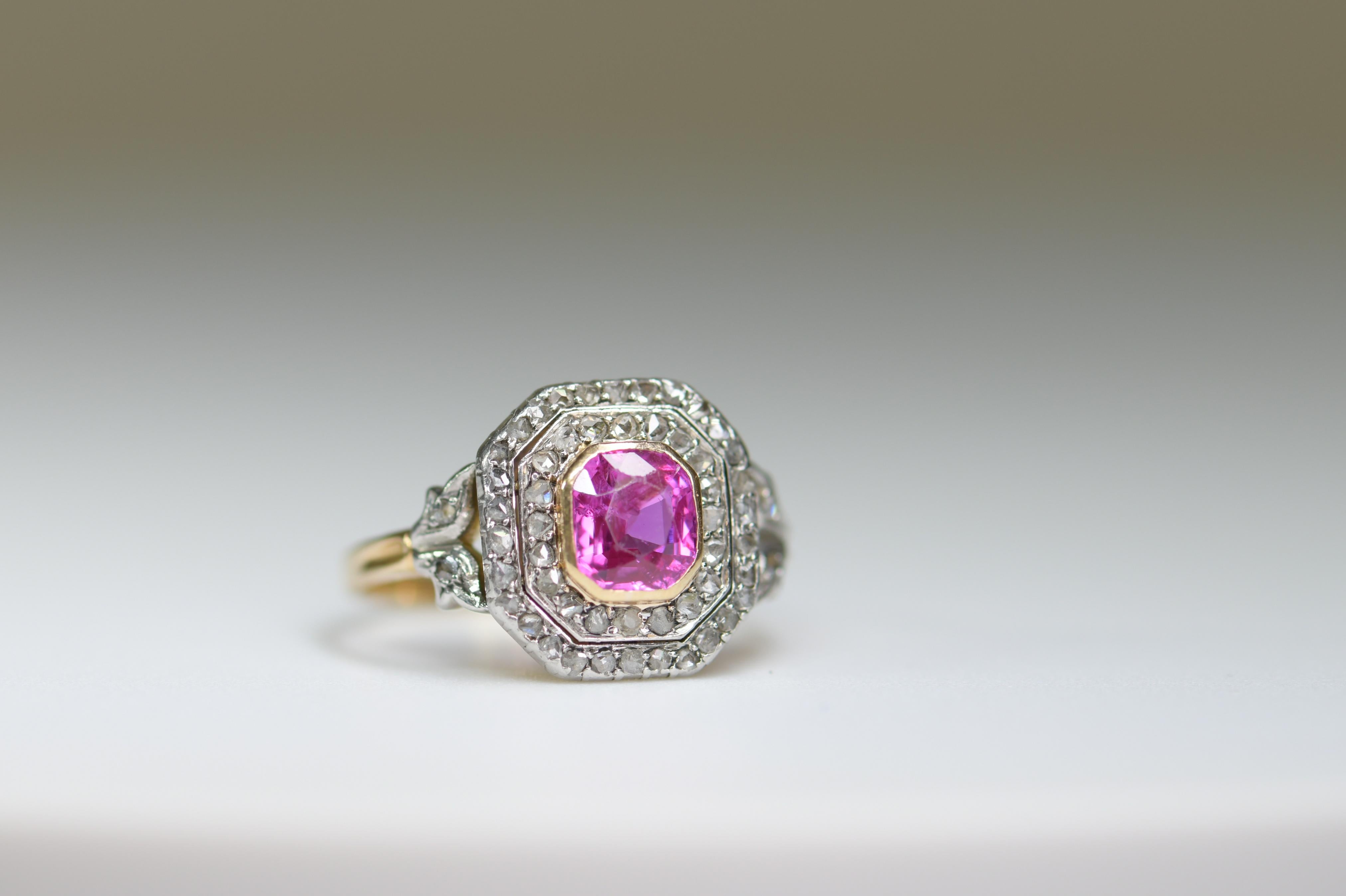 An unusual 18ct gold ring with a platinum top that was made circa 1900-1910. It has been set with a square shaped pink sapphire. It is surrounded by set with two rows of rose-cut diamonds, also seamed shoulders foliage of roses. It sits low on the