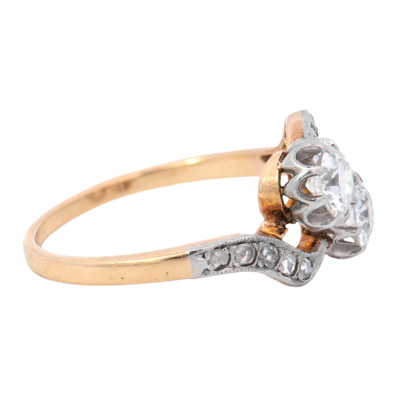 A unique and exquisite diamond bypass ring from the Edwardian (ca1910) era! Crafted in 18k yellow gold topped with Platinum, this piece features two Round Cut diamonds that are nestled together at the center, forming a stylish 