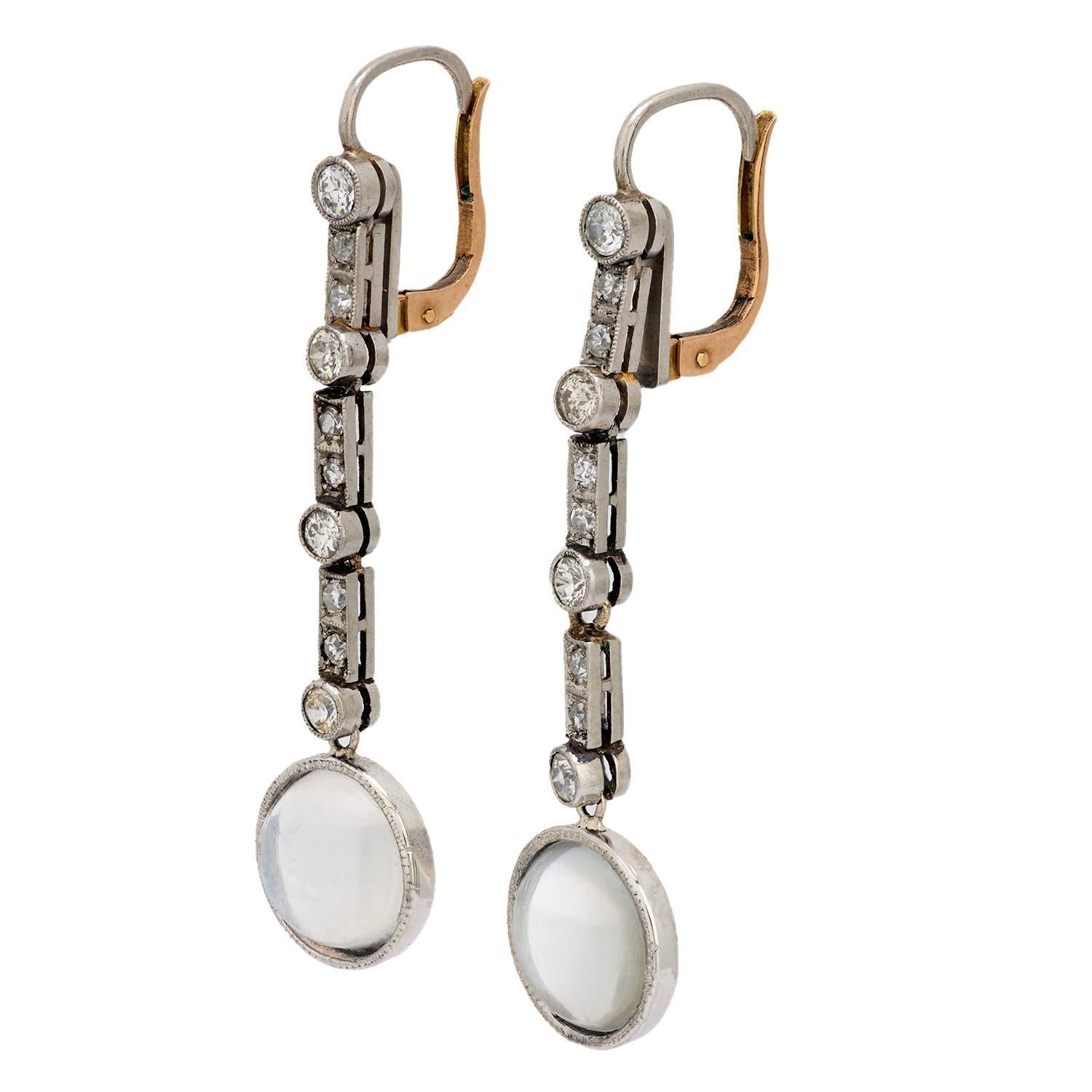 Uno squisito paio di eleganti orecchini con pietra di luna e diamanti di epoca edoardiana (ca. 1910)! Realizzati in platino e 18 carati, questi orecchini iniziano con una sottile e stretta maglia tempestata di diamanti. I diamanti variano nel taglio