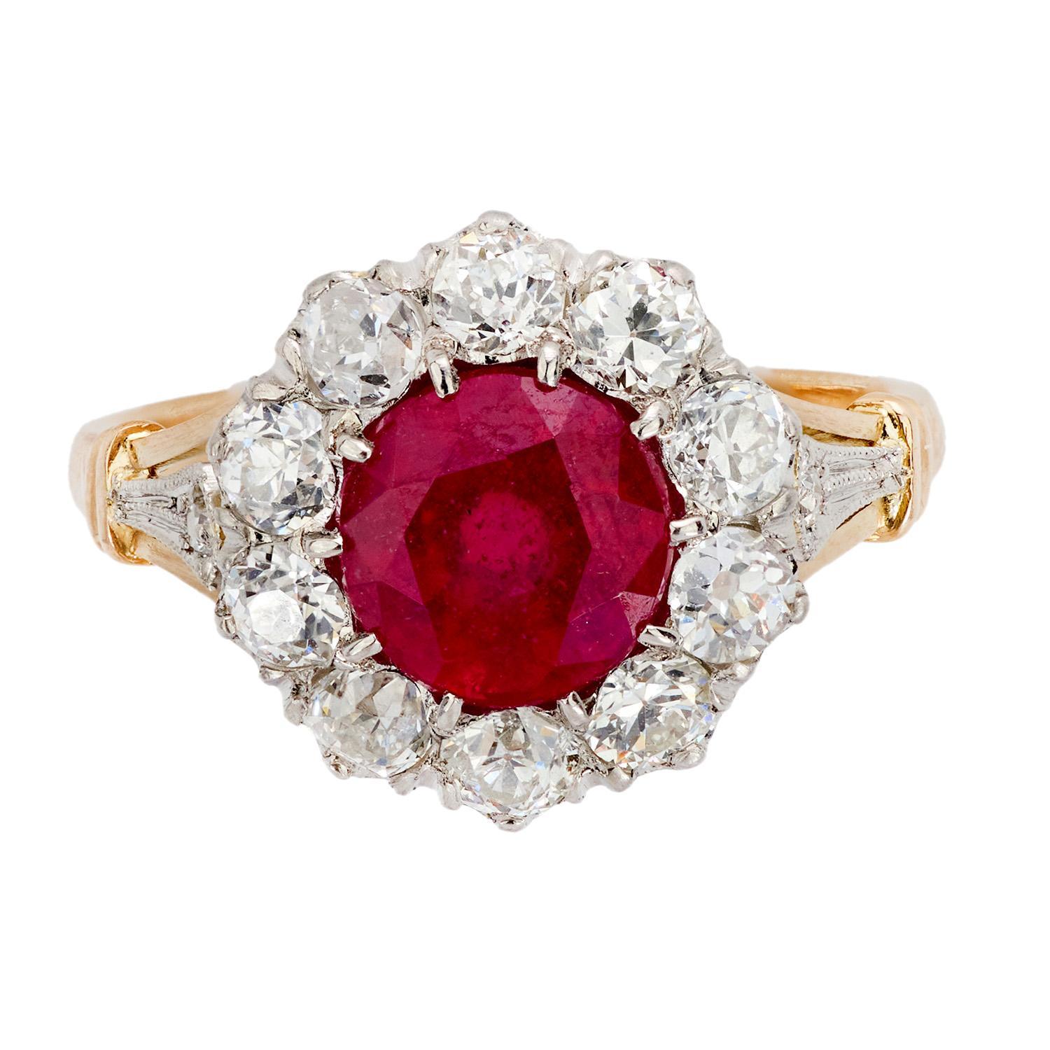 A gorgeous ruby and diamond halo ring from the Edwardian (ca1910s) era! This outstanding ring is crafted in vibrant 18k yellow gold and topped in platinum. The piece features a central Burmese round cut ruby, which has an approximate carat weight of