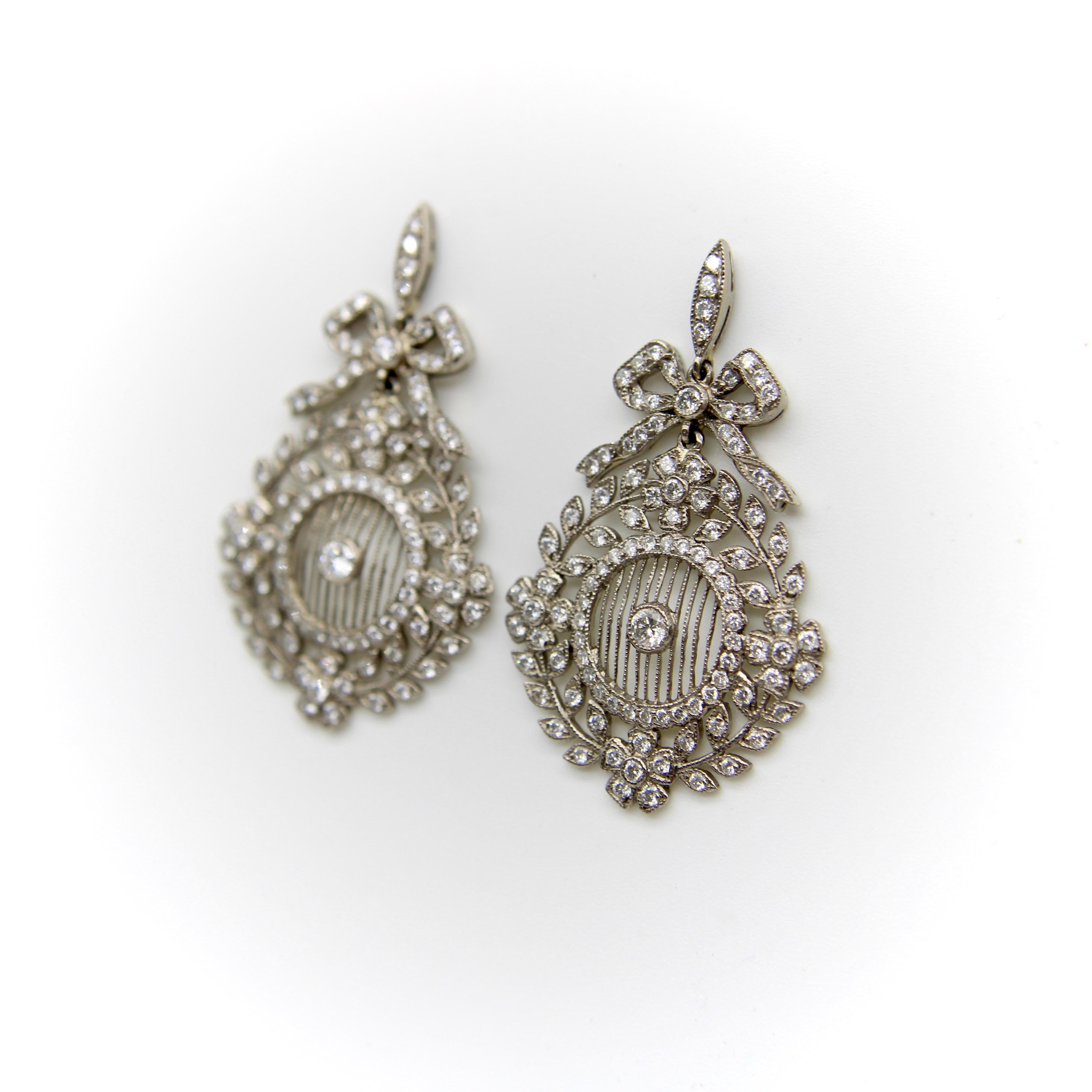 Diese edwardianischen Ohrringe aus 18 Karat Weißgold sind mit eingefassten Diamanten besetzt und mit filigranen Verzierungen versehen. Sie bieten viel Bewegung, da der untere Teil des Ohrrings - ein Blumenkranz - an dem bandförmigen oberen Teil, der