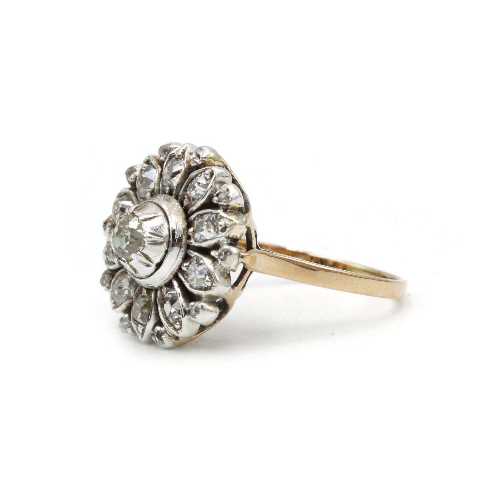 This delicate Edwardian-era cluster ring showcases a central old European–cut diamond (approx. 0.15 ct) encircled by a petal of twelve smaller old-cut diamonds, all set in a finely pierced 18K yellow gold mounting. Crafted circa 1900–1910, the