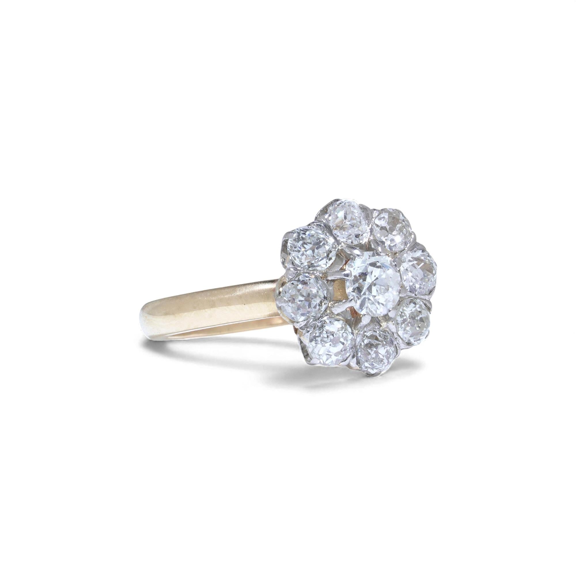 An Edwardian period daisy-cluster ring set with bright old European-cut diamonds in a classic floral arrangement. The centre stone is framed by eight matching outer diamonds, all mounted in platinum-topped settings above an 18kt gold band. A refined