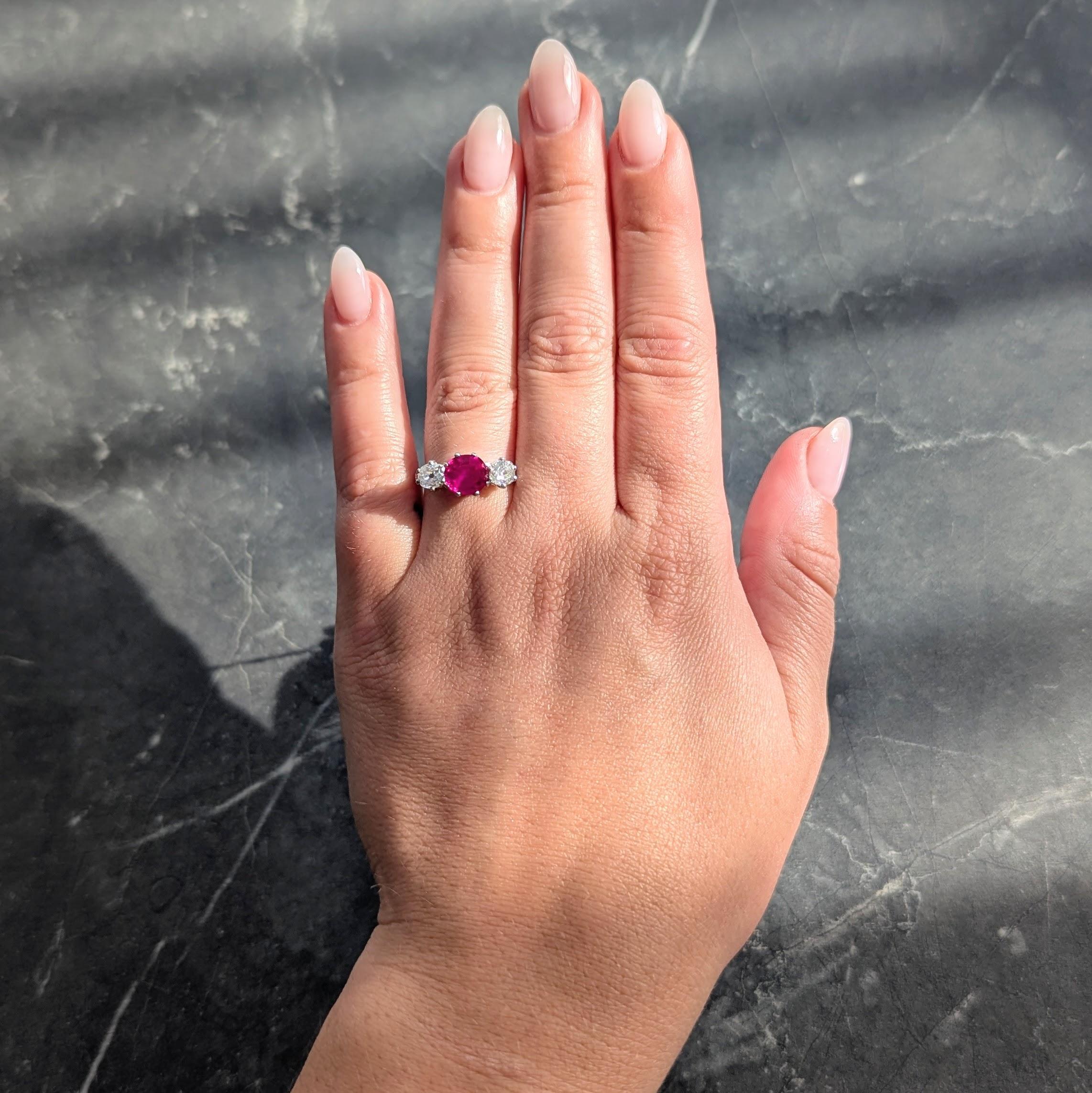 Centering a cushion cut ruby weighing 1.12 carats - transparent medium purplish red in color
Natural Burmese in origin and displaying no indications of heat treatment
Prong set and flanked by prong set old mine cut diamonds
Weighing approximately