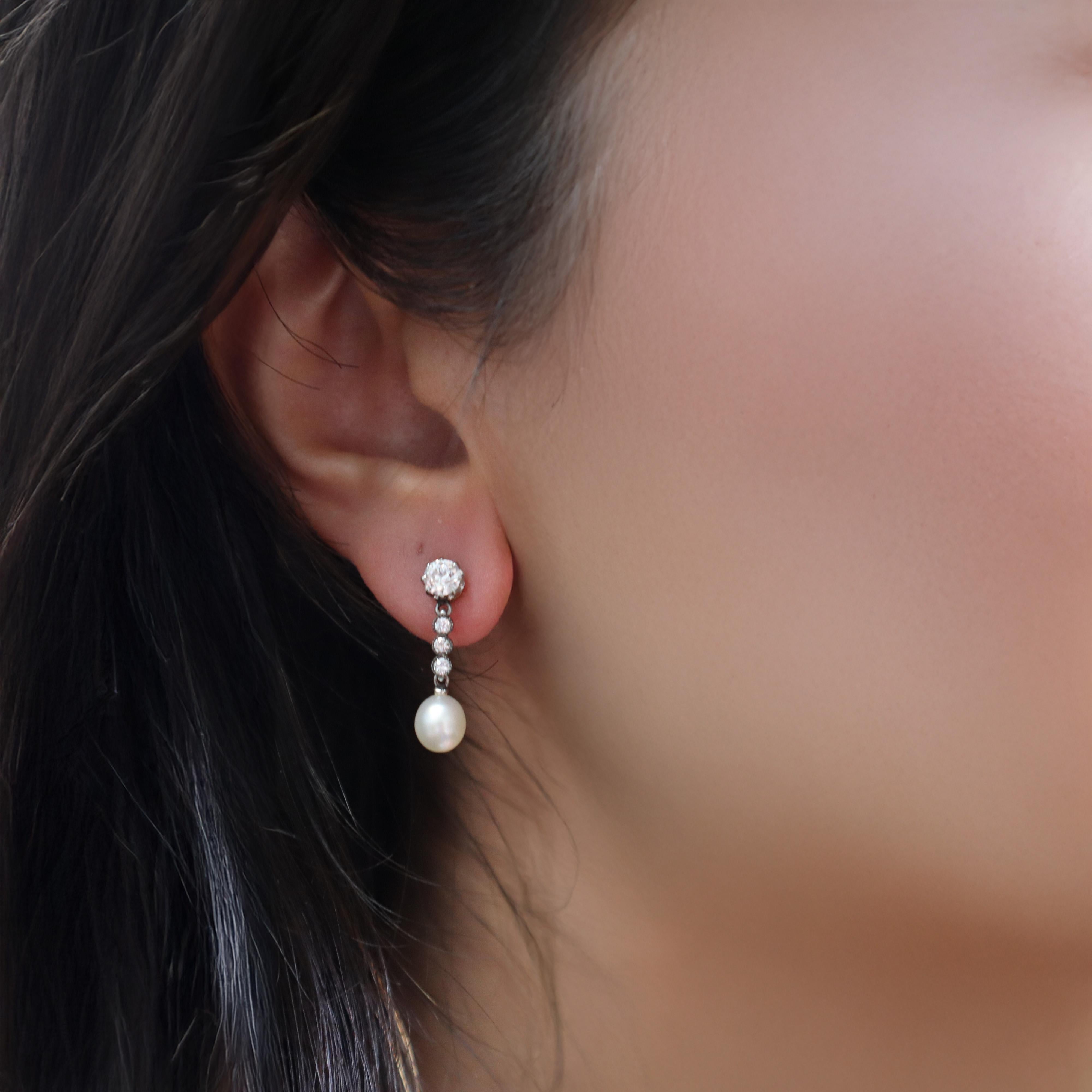 This exquisite pair of antique drop earrings exemplifies the refined elegance of the Edwardian era, beautifully crafted in lustrous 18kt rose gold with platinum detailing during the 1910s and featuring two stunning natural pearls, approximately