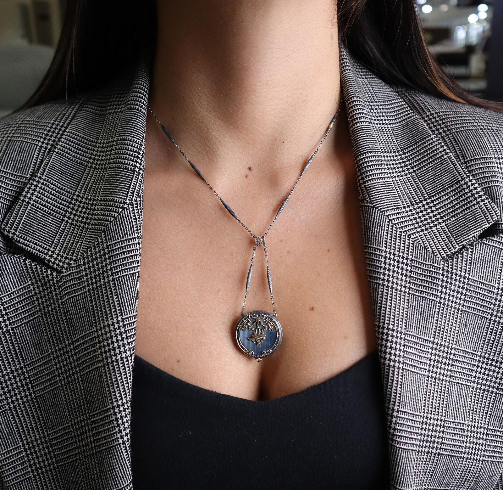 Presenting an exquisite Edwardian lavalier necklace crafted in 18 karat gold, featuring a finely detailed guilloche enamel design. The centerpiece is an antique pocket watch, beautifully accented with natural rose cut diamonds (approx. 0.05 carats),